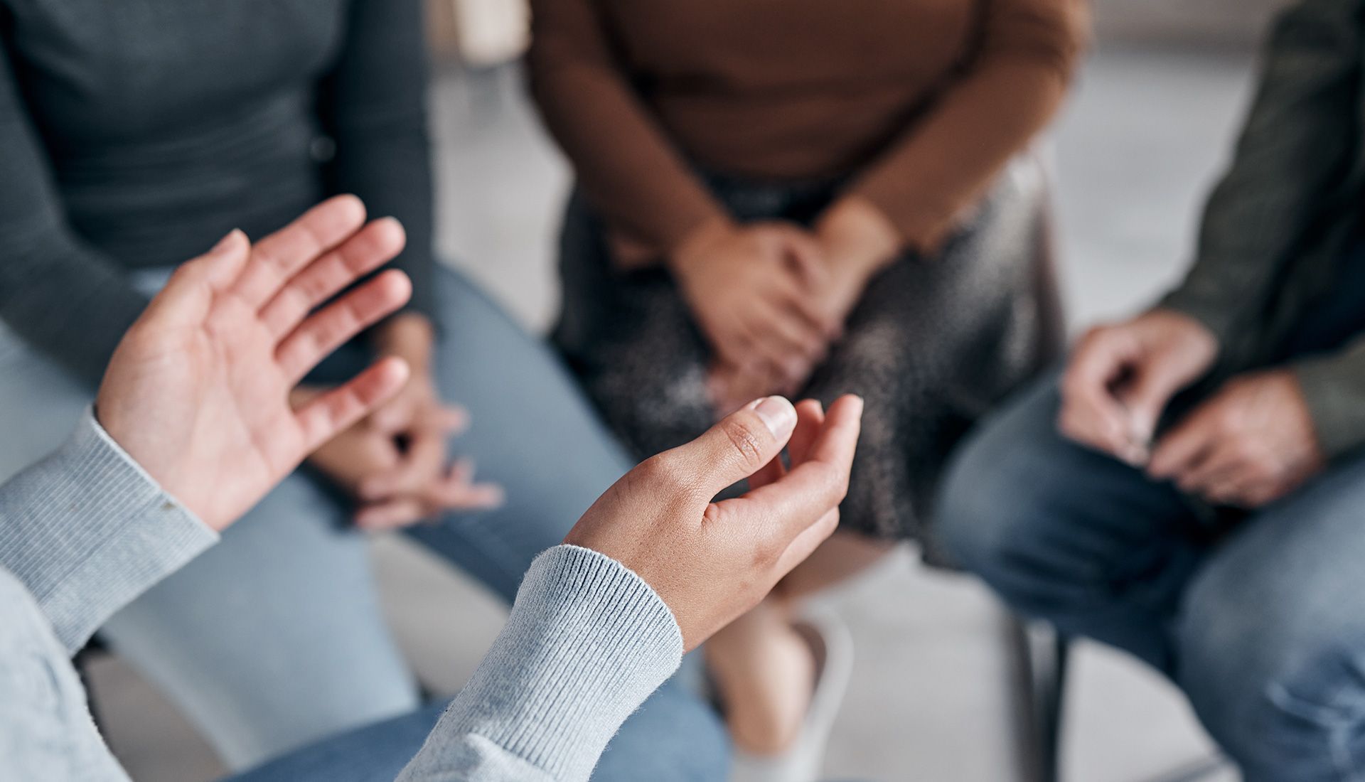 Hands gesturing in a circle of people, likely a group therapy session.