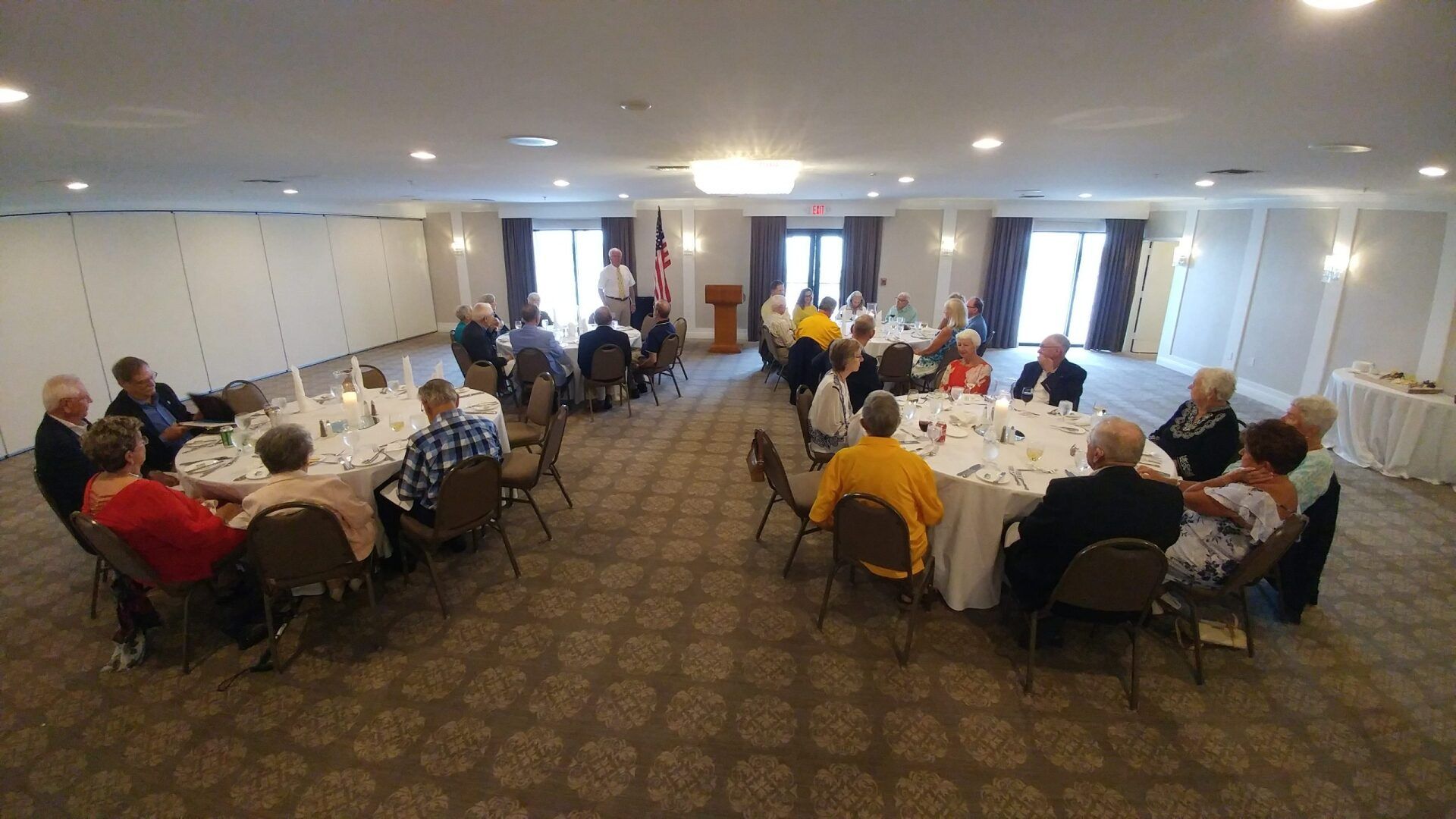 People seated at round tables in a ballroom, likely attending an event.