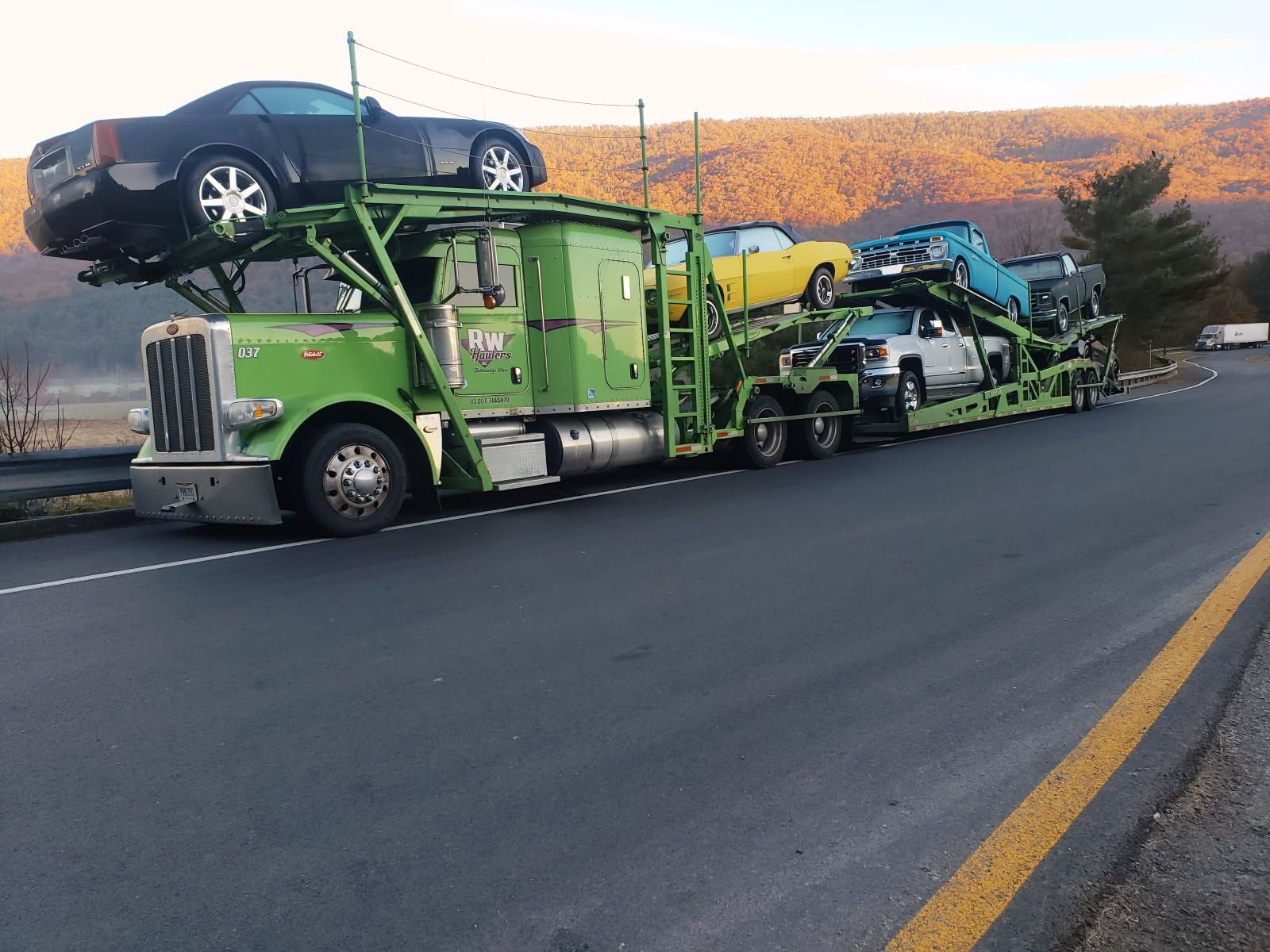 RW Hauler truck carrying classic cars down a highway road