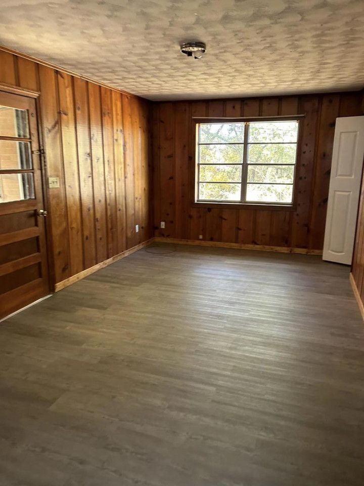 an empty room with wood paneling and a window .