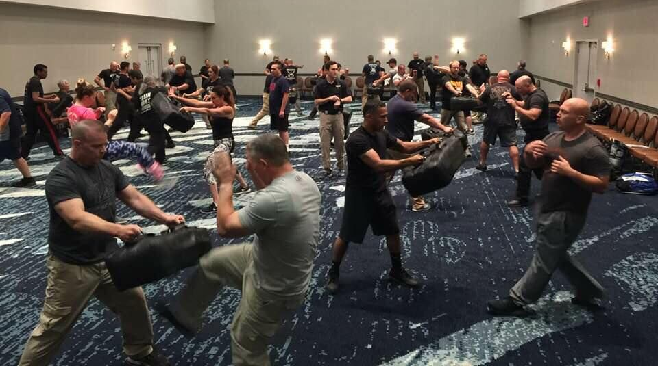 Two police officers standing next to a black suv in a parking lot