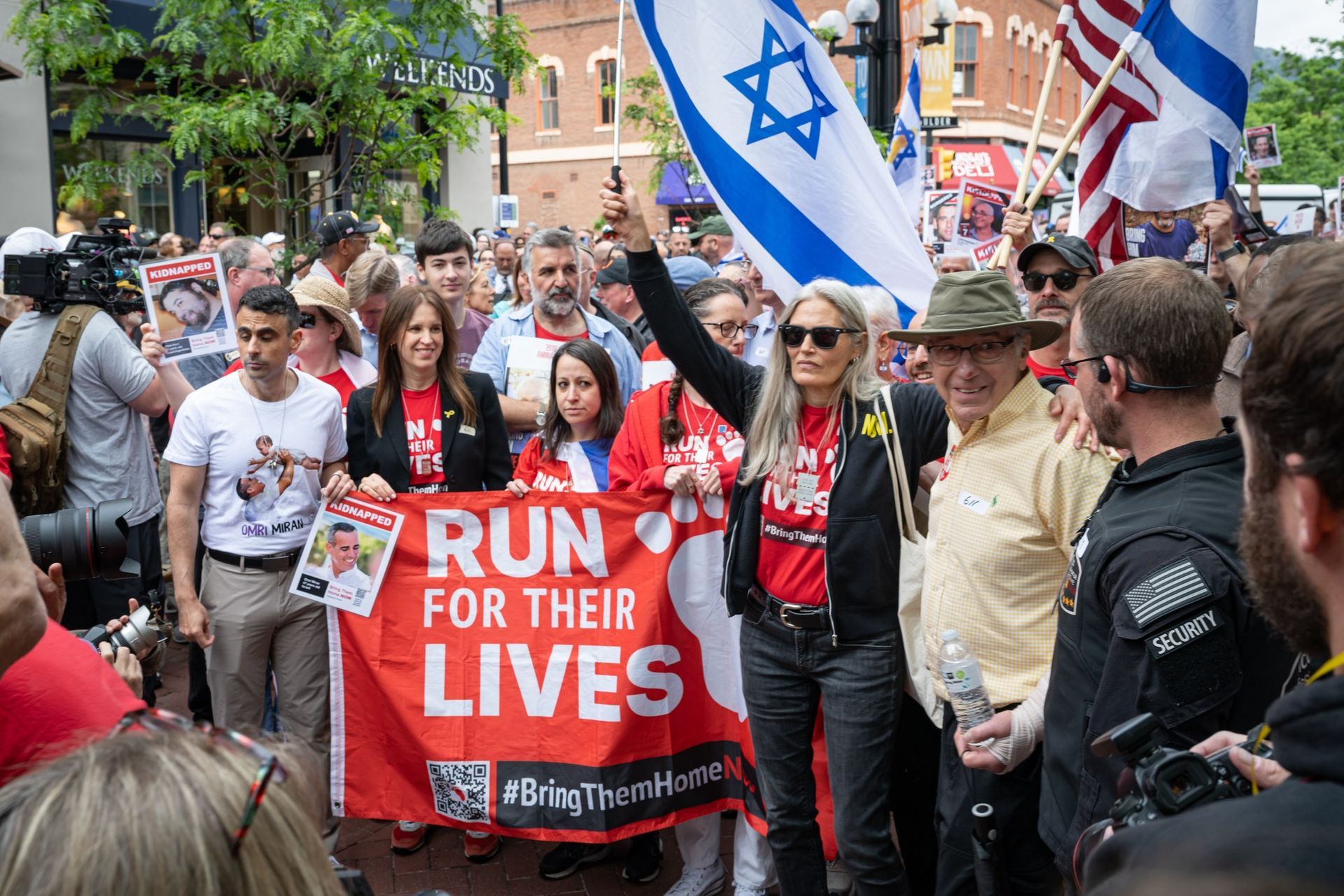 People march, holding Israeli flags and a banner that reads 