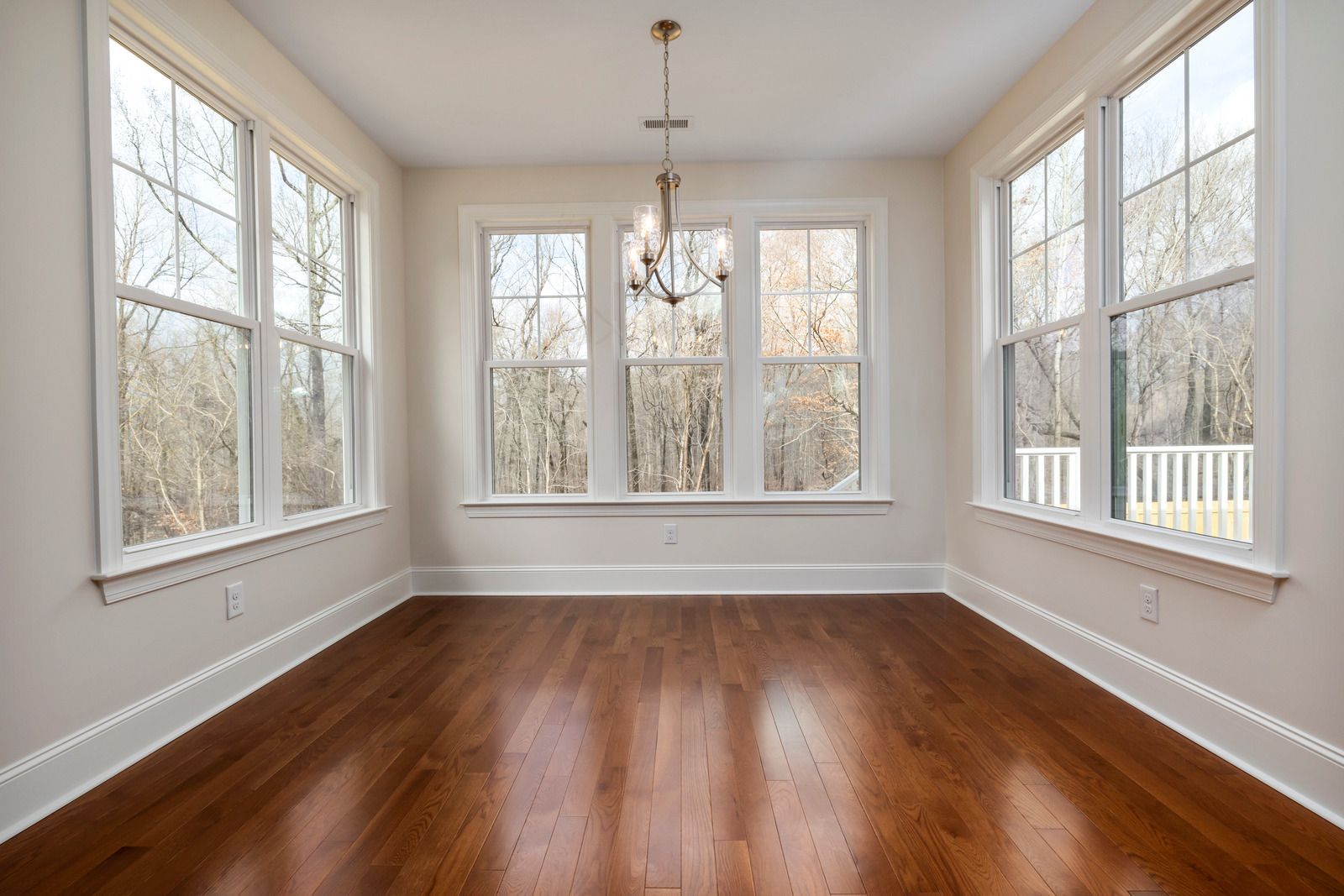 An empty room with hardwood floors and lots of windows.