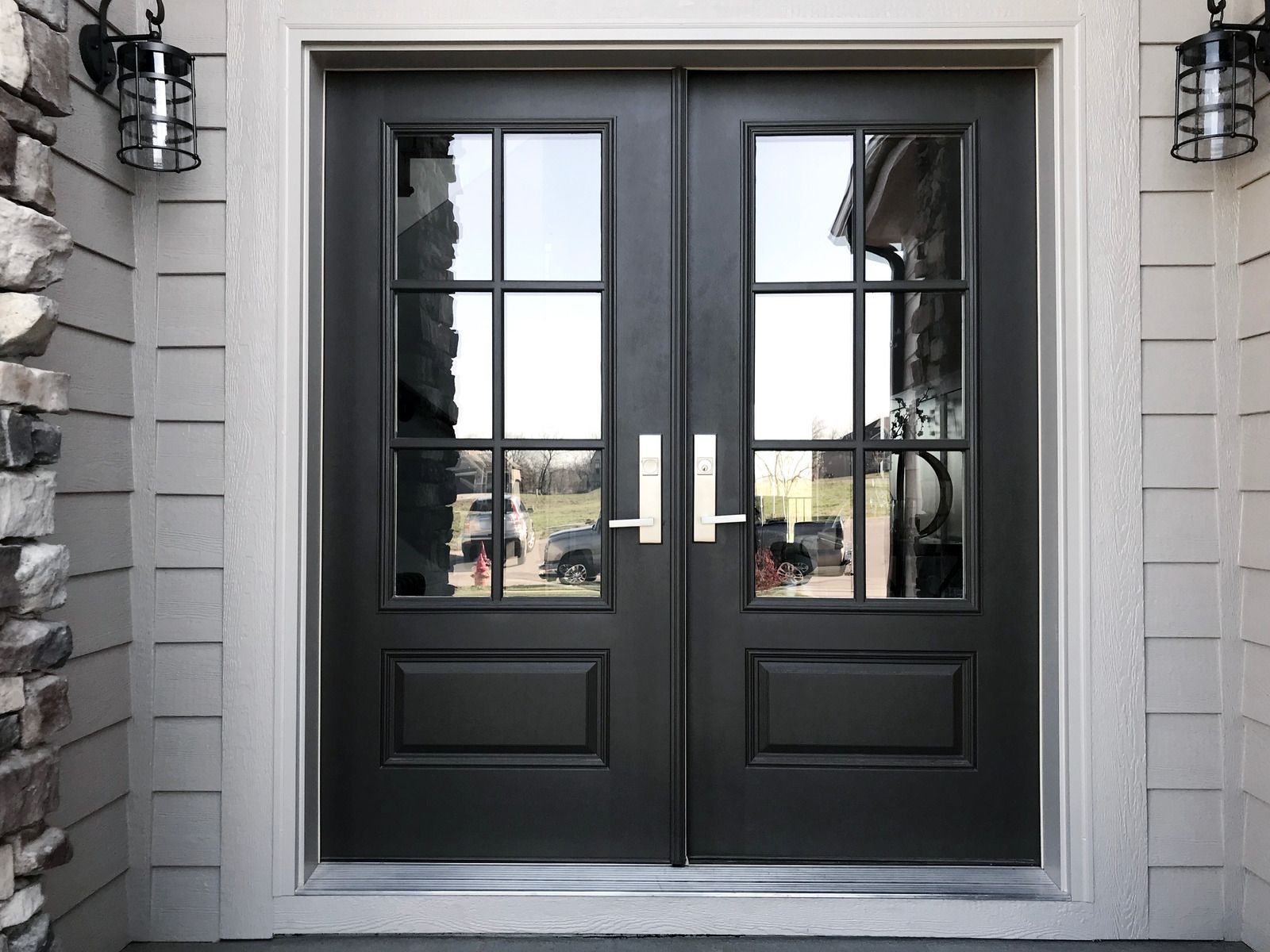A black double door with a lot of windows on a house.