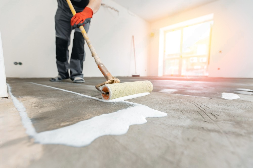 a man is using a paint roller to paint the floor