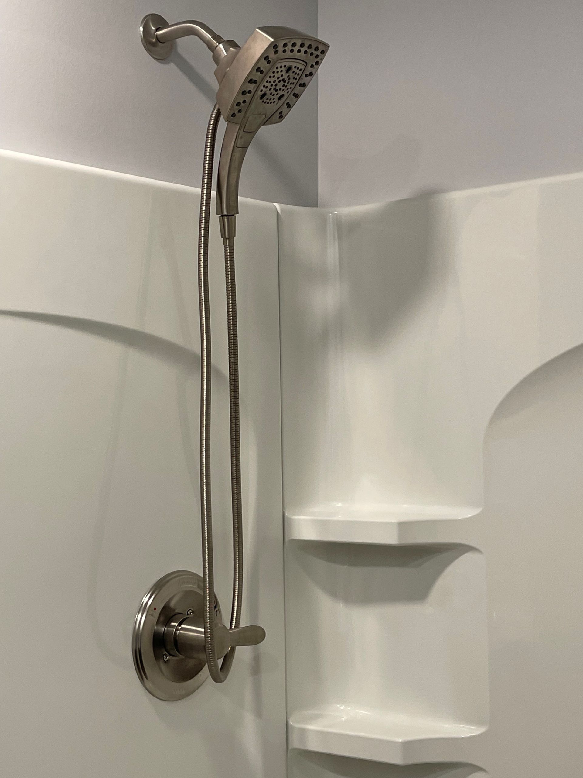 A shower head is hanging from the ceiling in a bathroom.