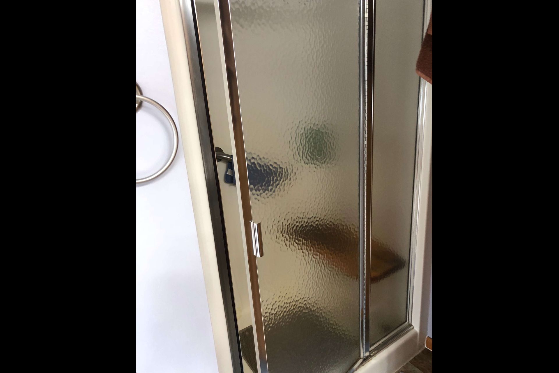 A bathroom with a glass shower door and a towel rack.