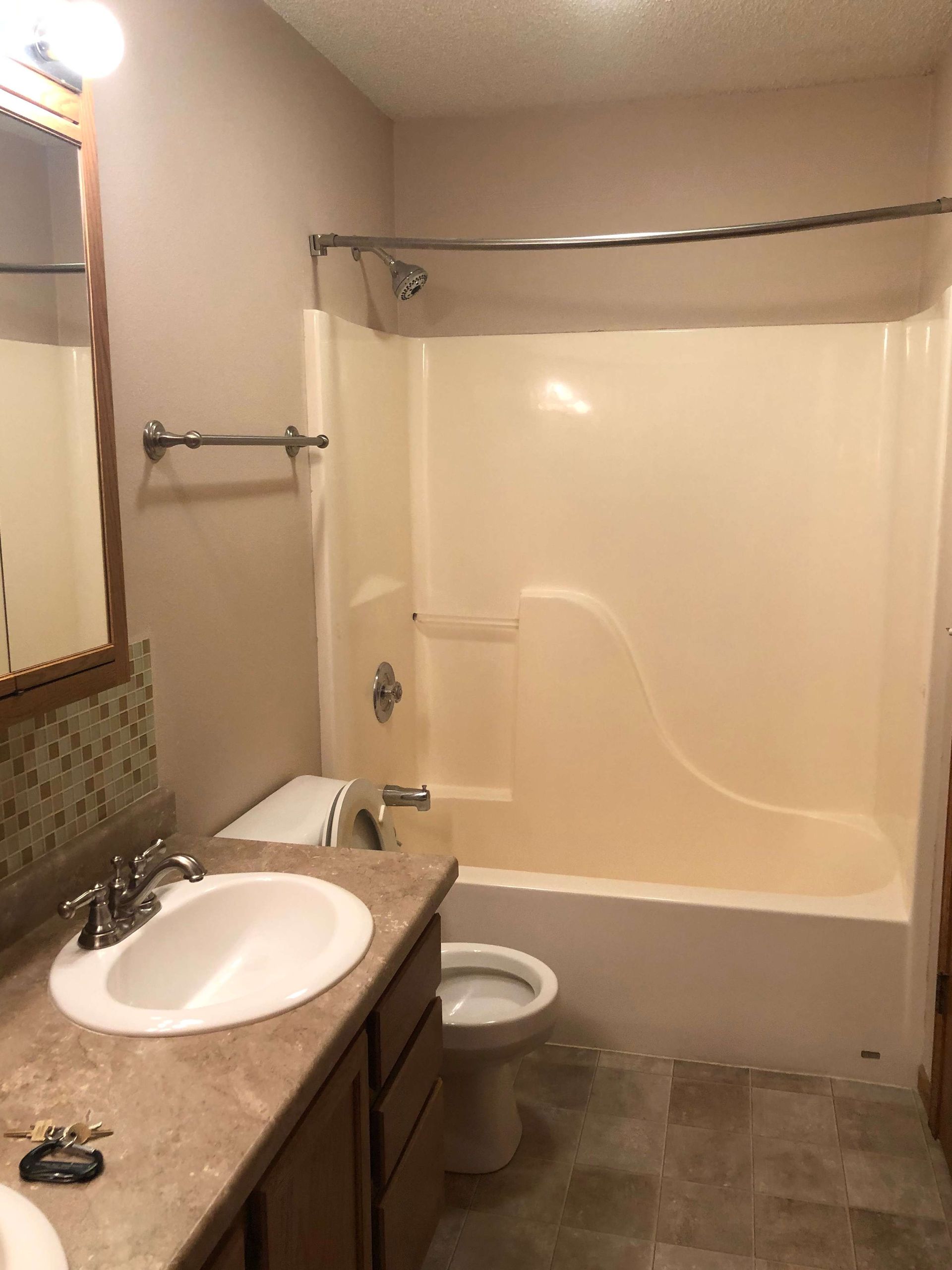 A bathroom with a sink , toilet , bathtub and mirror.