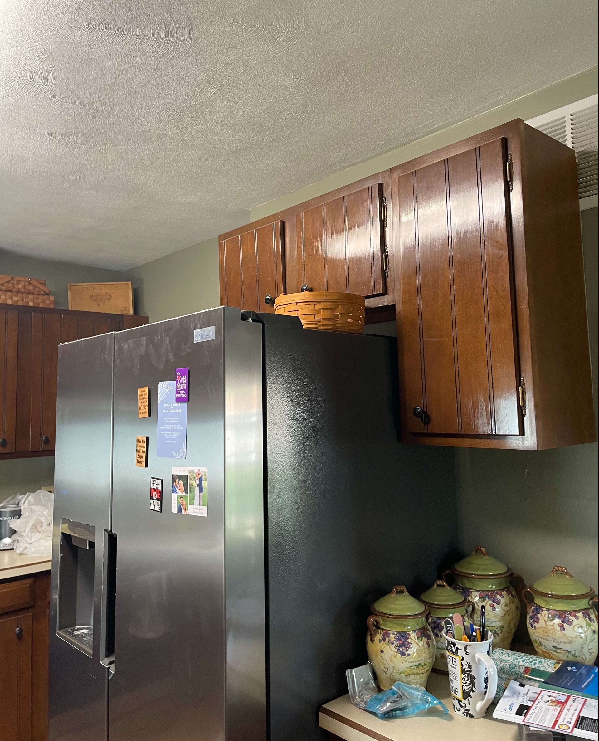 A kitchen with a stainless steel refrigerator and wooden cabinets