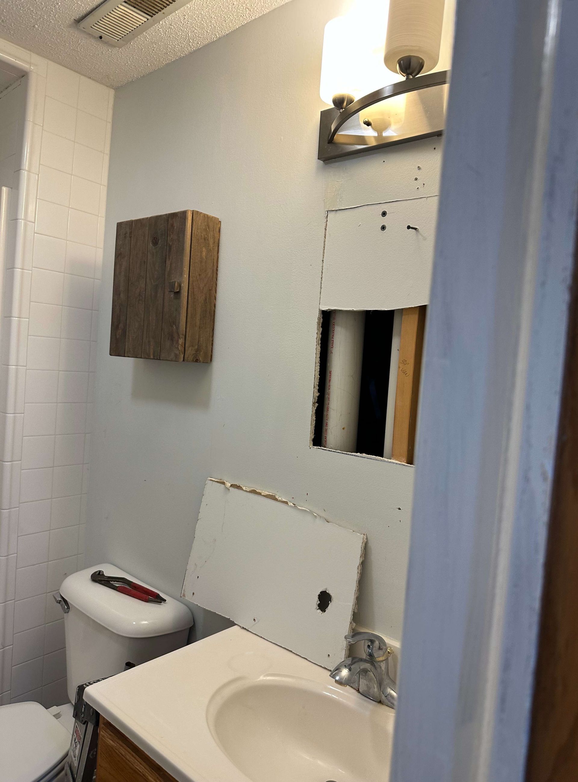 A bathroom with a toilet , sink and mirror.