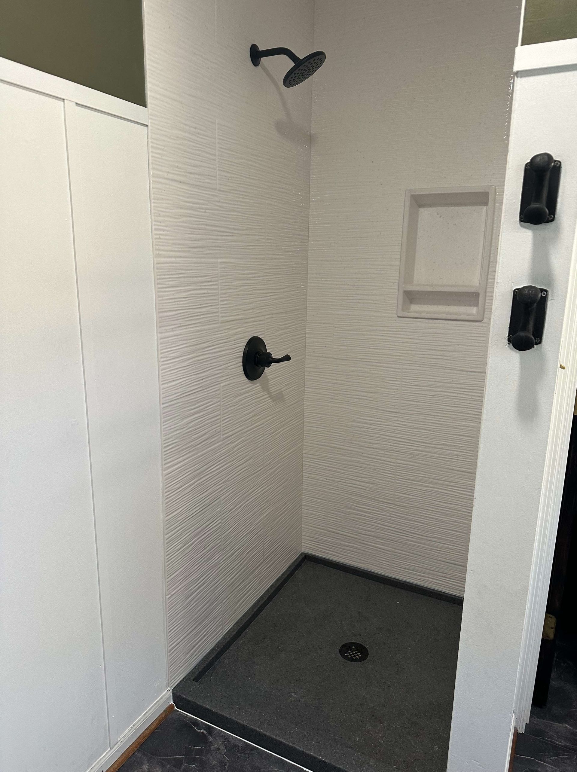 A shower stall with a black shower head in a bathroom.