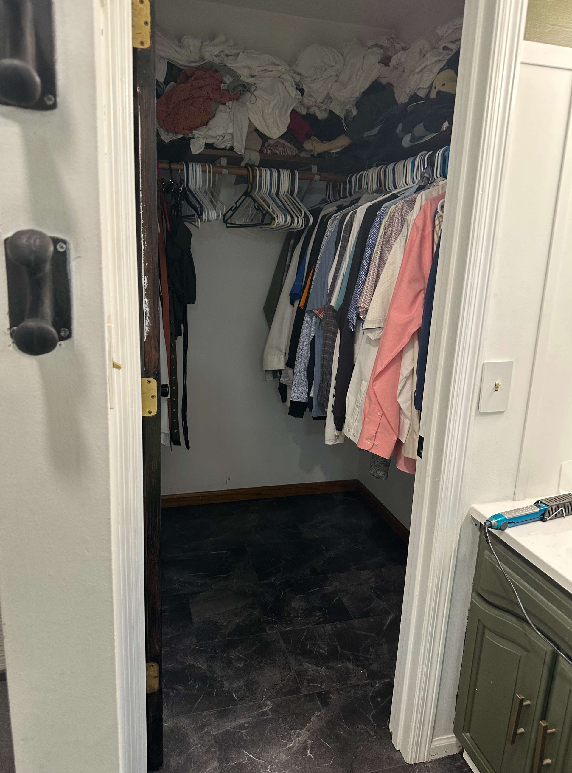 A walk in closet filled with clothes and a bathroom.