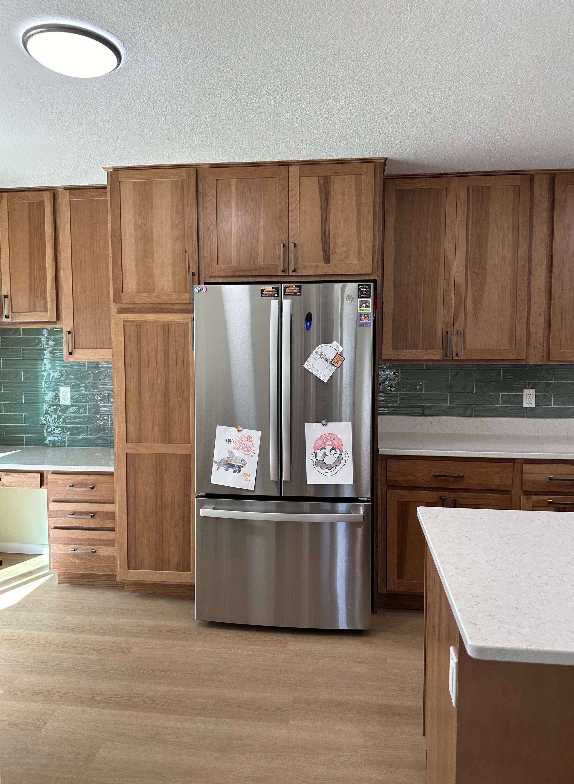A kitchen with wooden cabinets and a stainless steel refrigerator