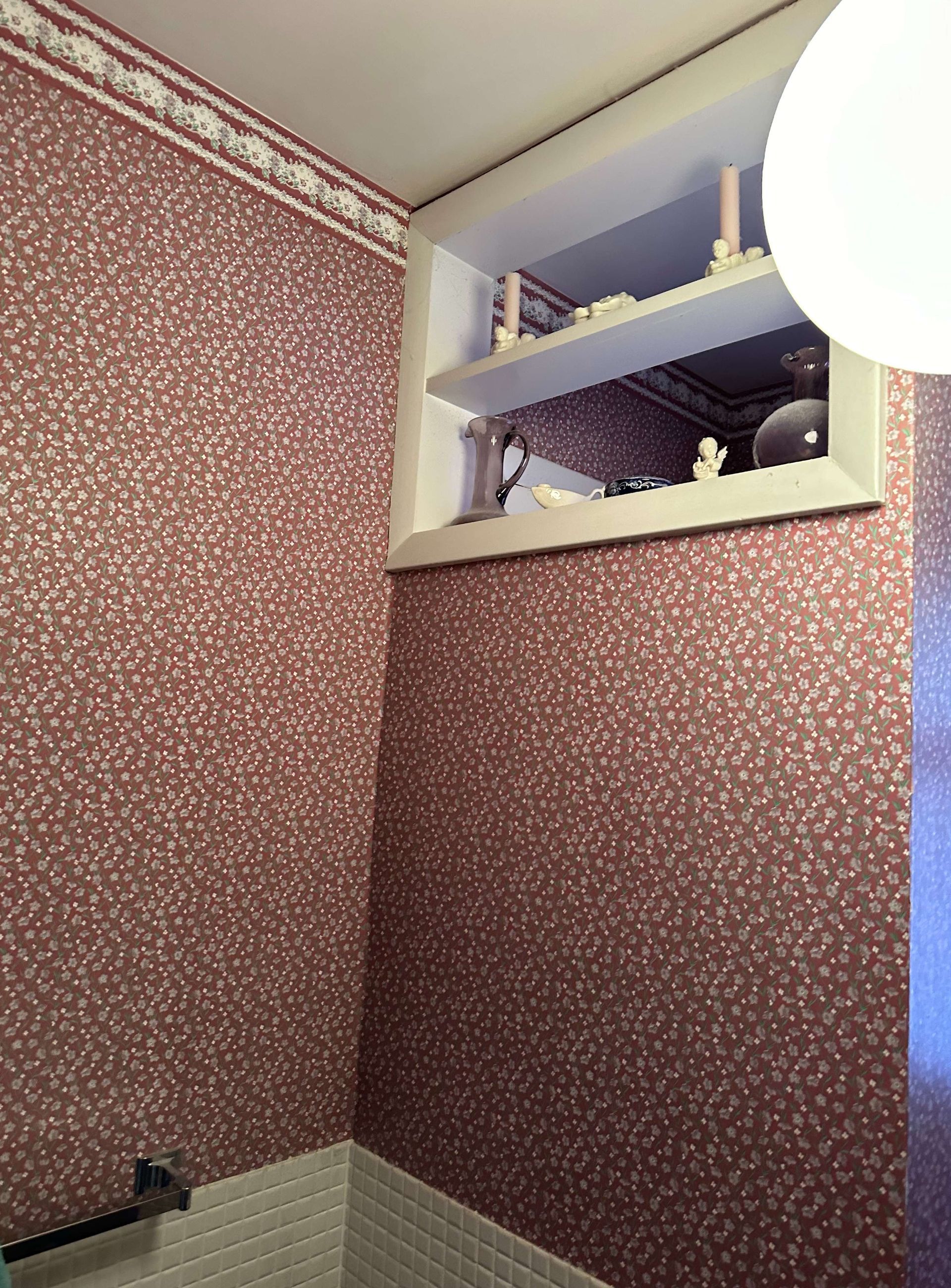 A bathroom with a window and a shelf with candles on it