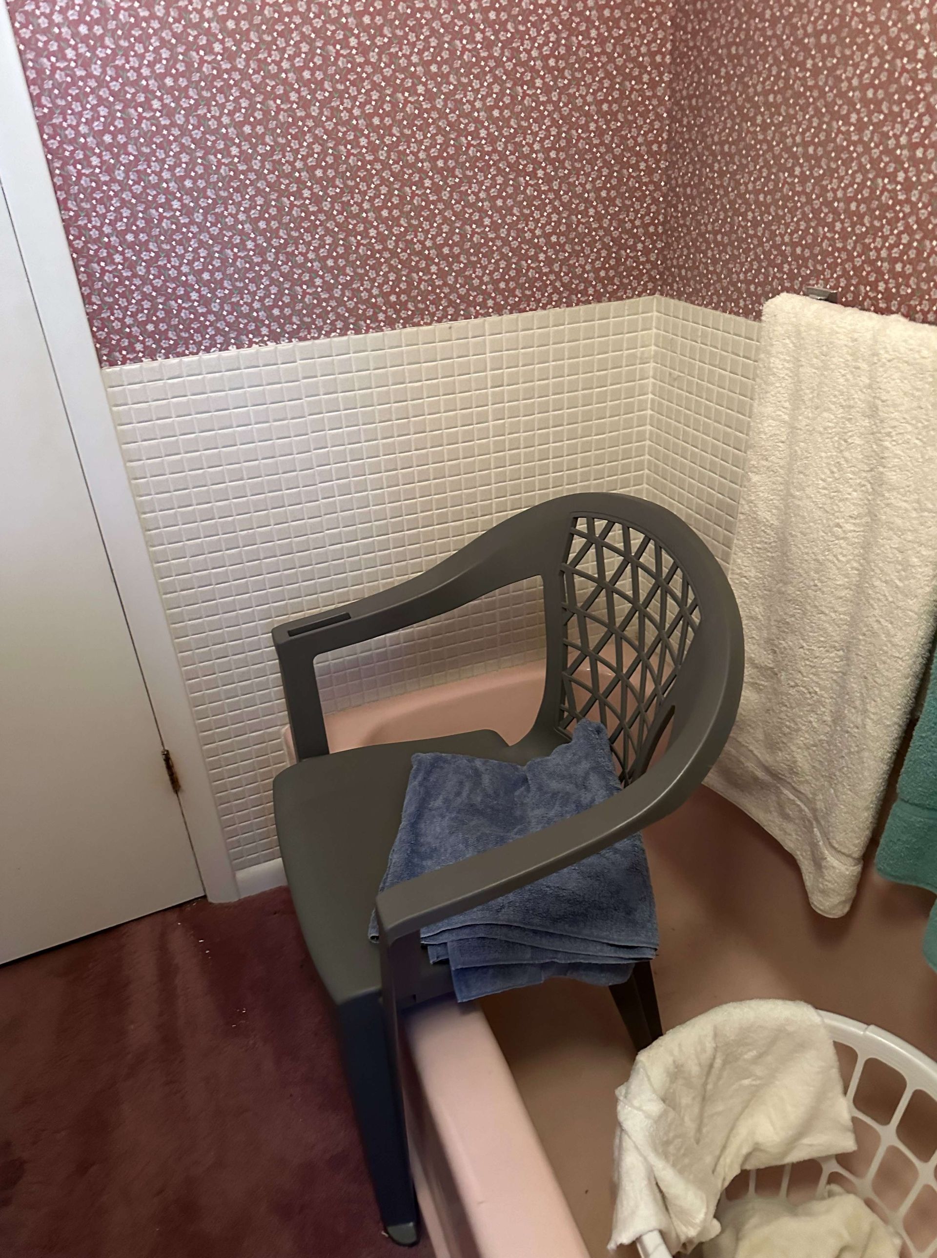 A chair is sitting in a bathroom next to a laundry basket.
