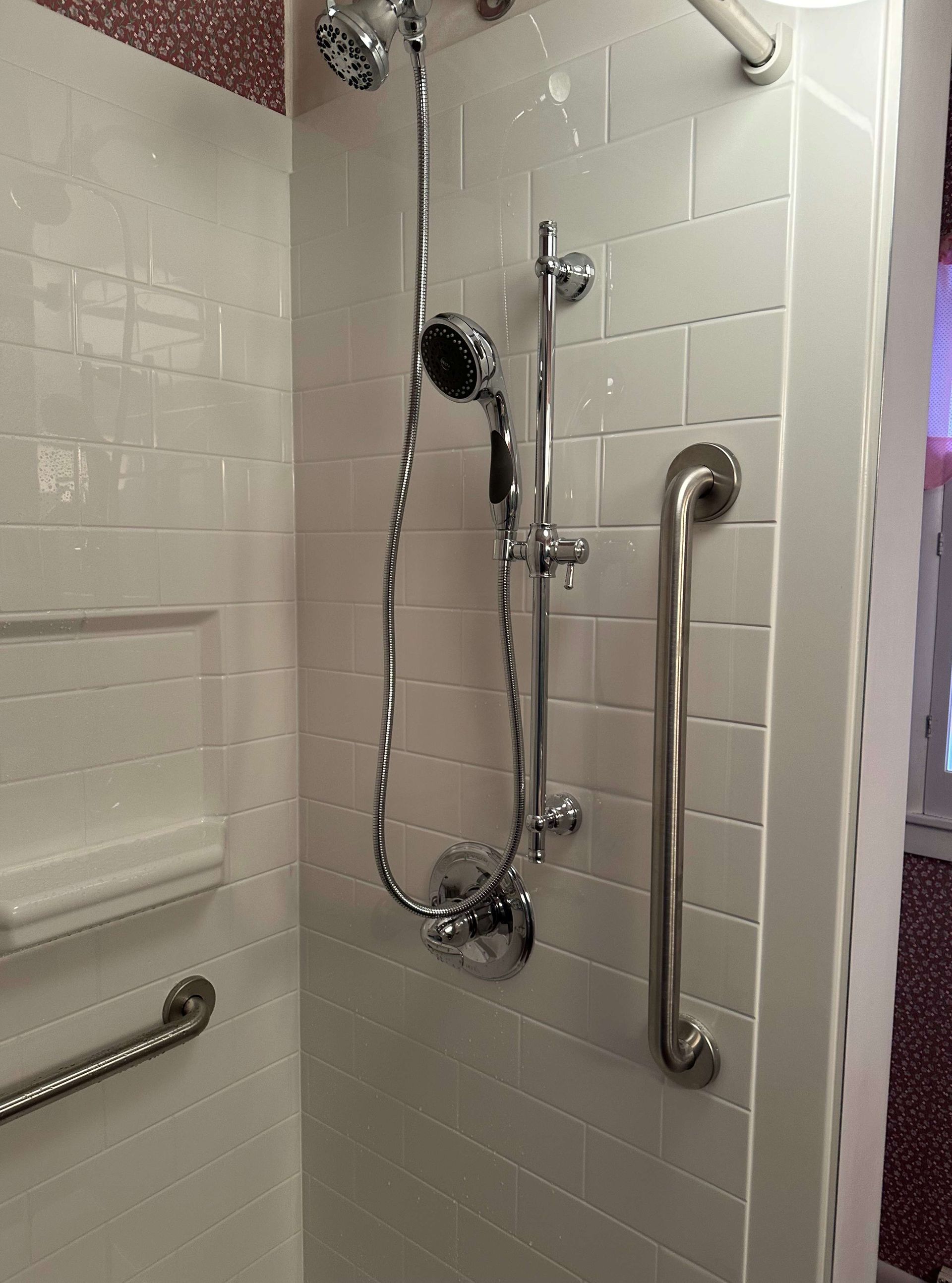 A shower with a hand rail and a shower head