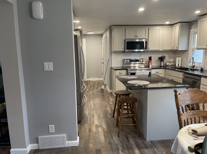 A kitchen with white cabinets , stainless steel appliances , granite counter tops and a large island.