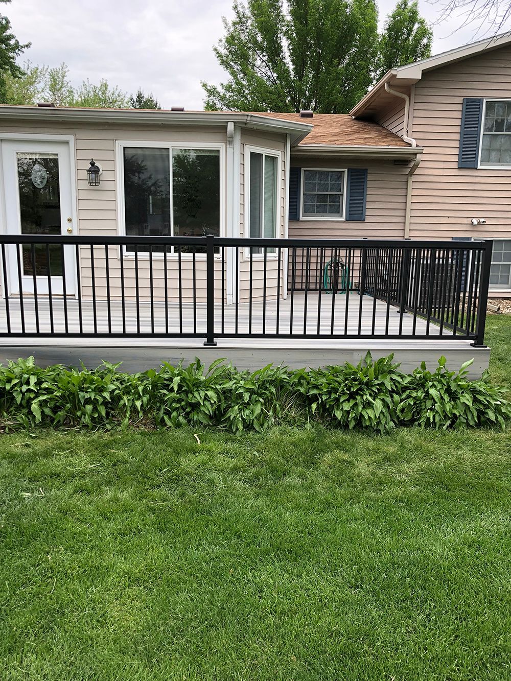 A house with a deck and a fence in front of it.