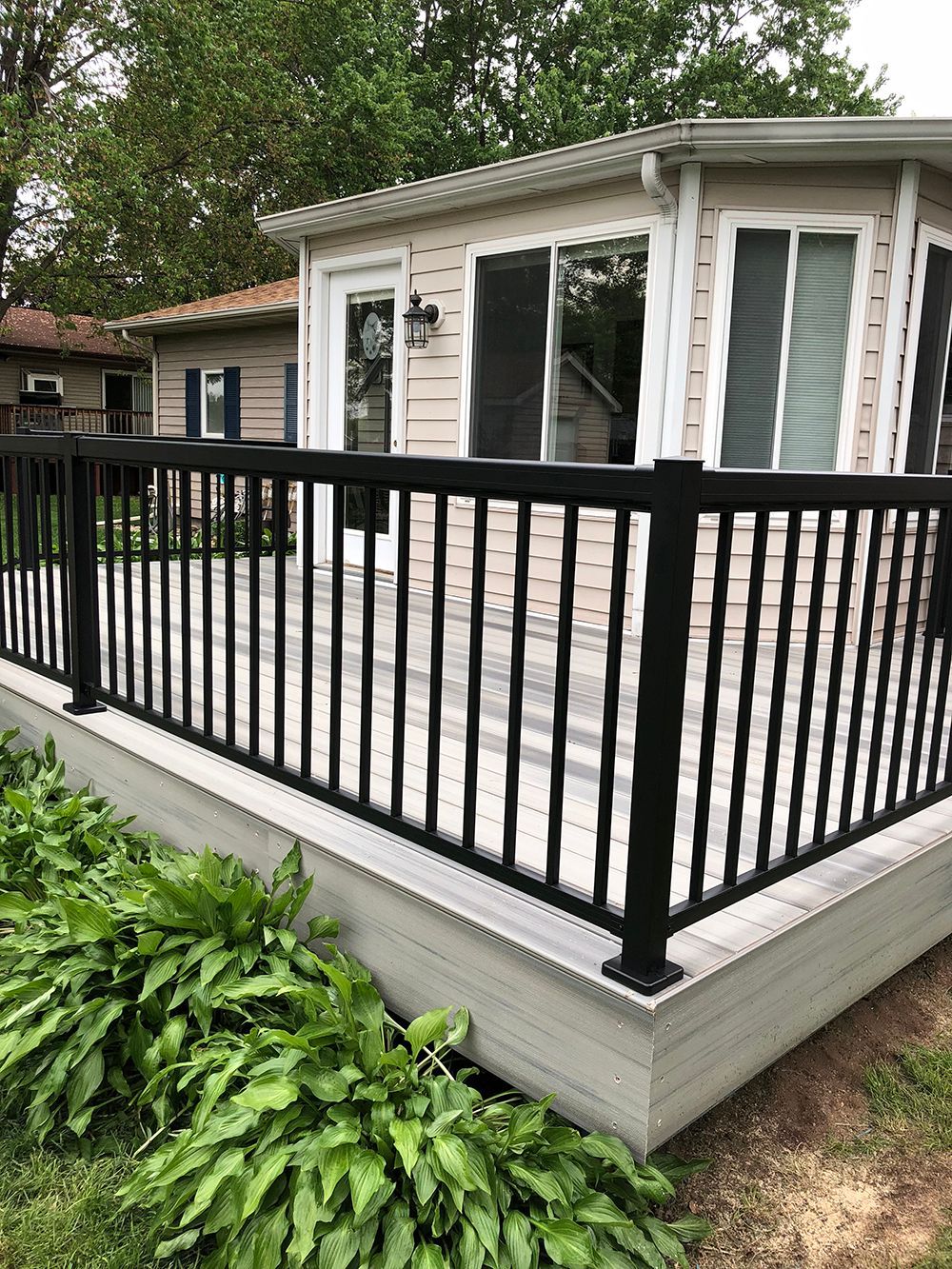 A small house with a deck and a black railing.