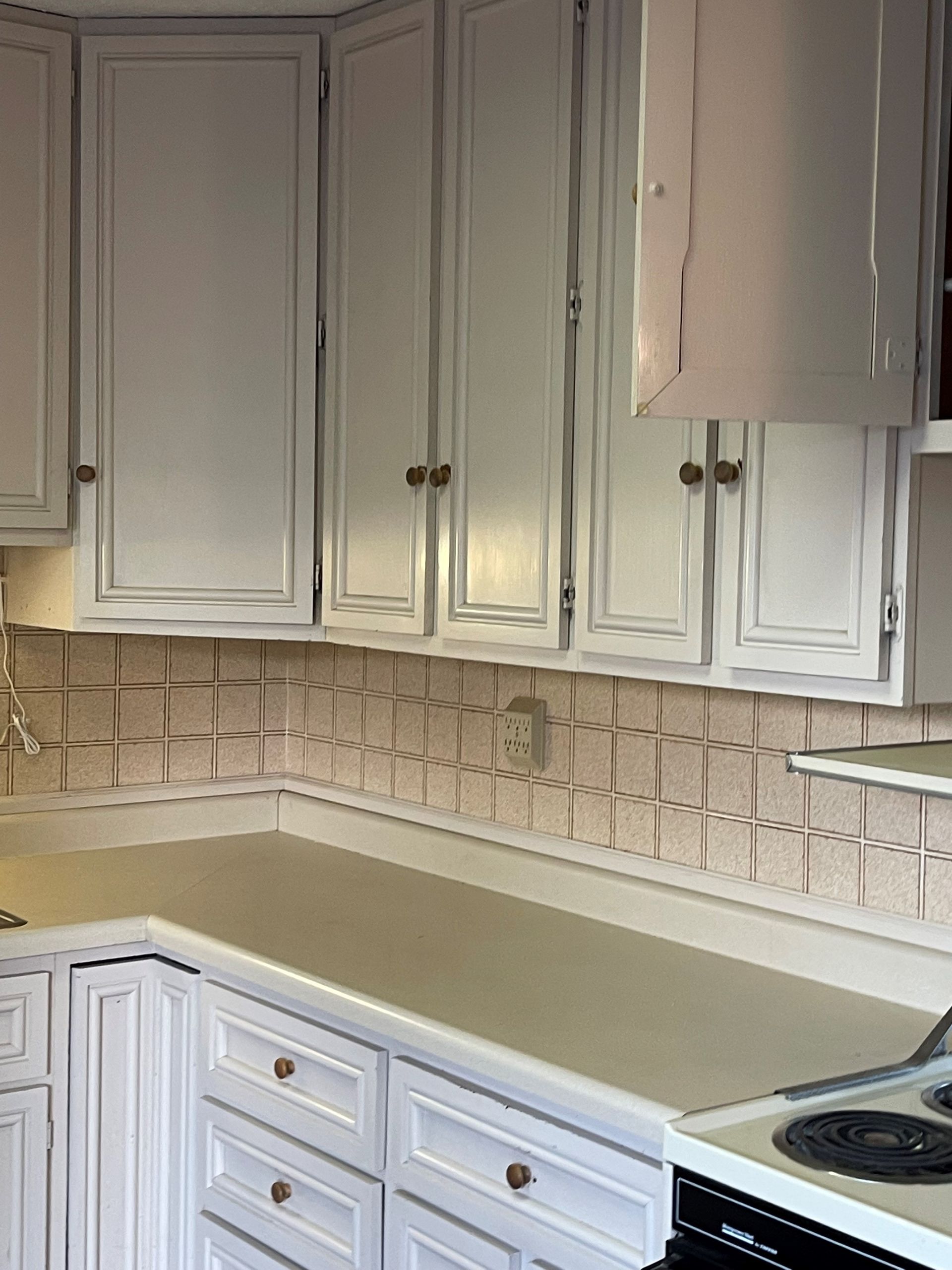 A kitchen with white cabinets and a stove top oven