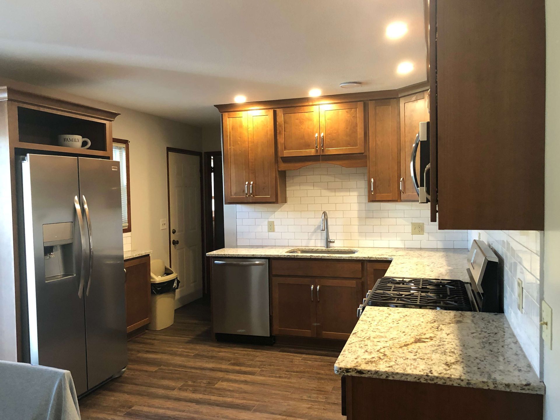 A kitchen with wooden cabinets , granite counter tops , stainless steel appliances and a refrigerator.