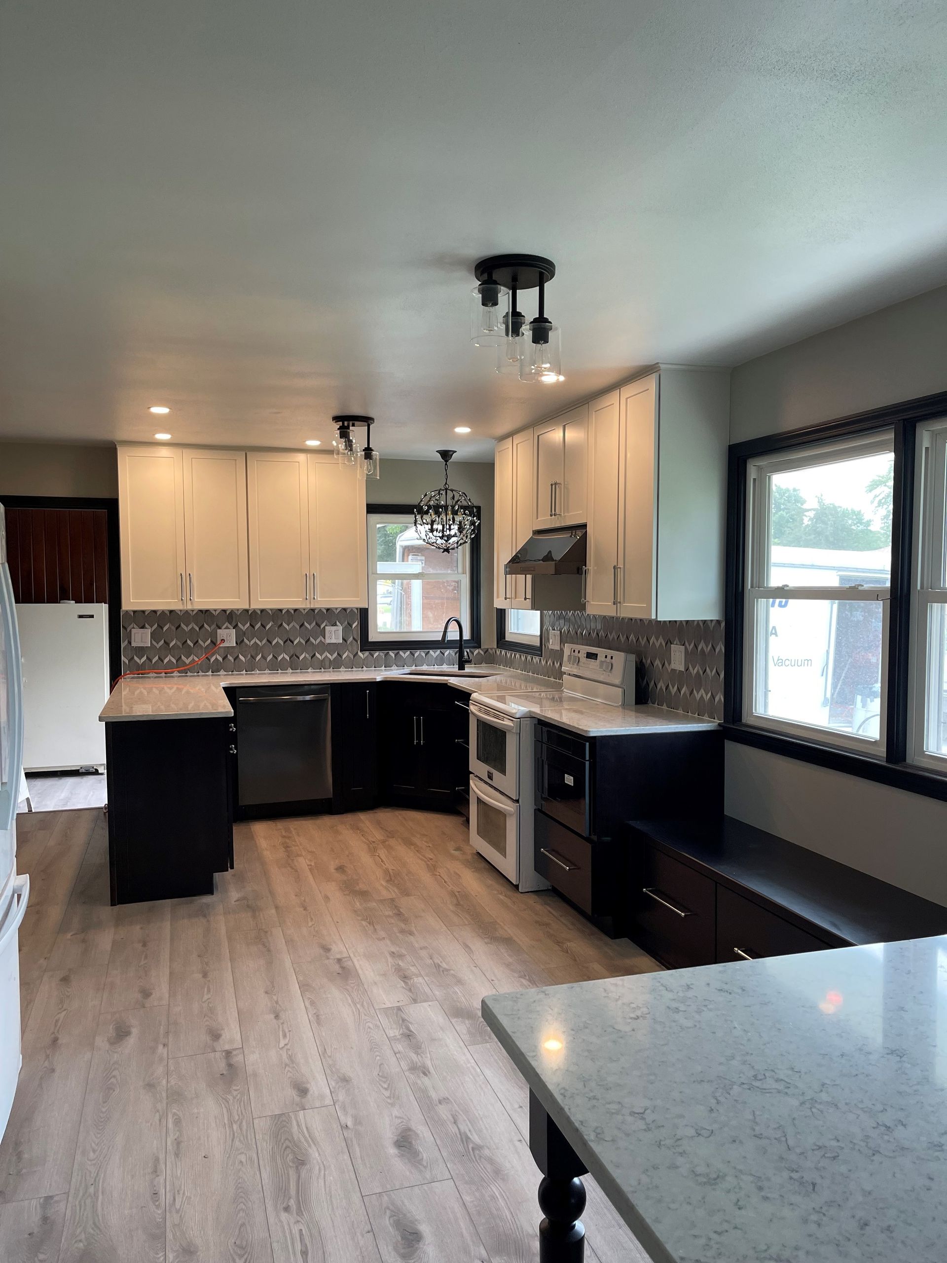 A kitchen with wooden floors , white cabinets , stainless steel appliances and a table.