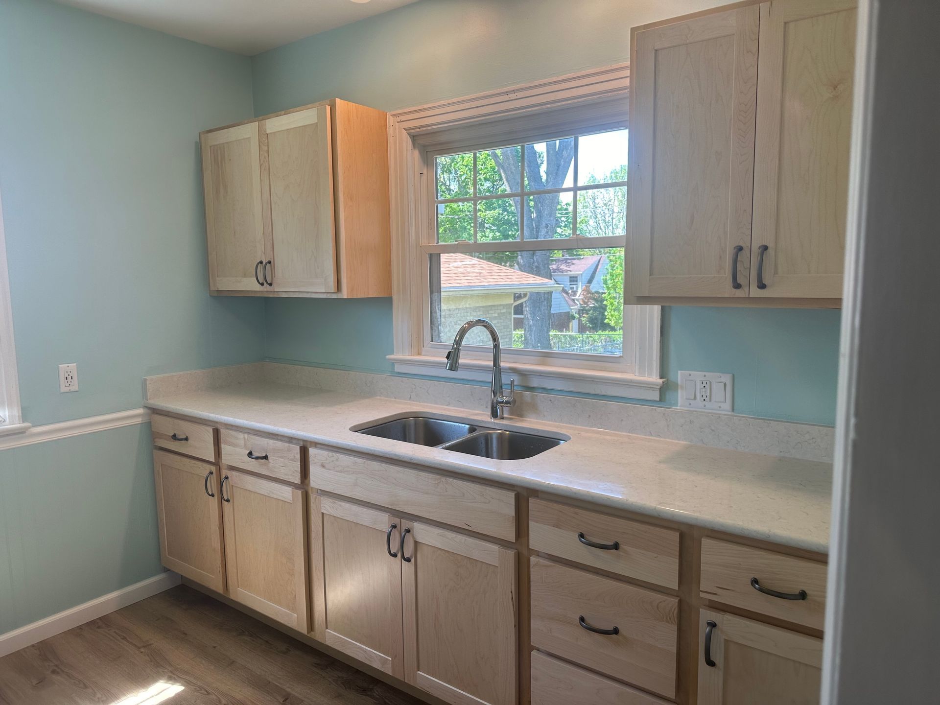 A kitchen with two sinks , cabinets , and a window.