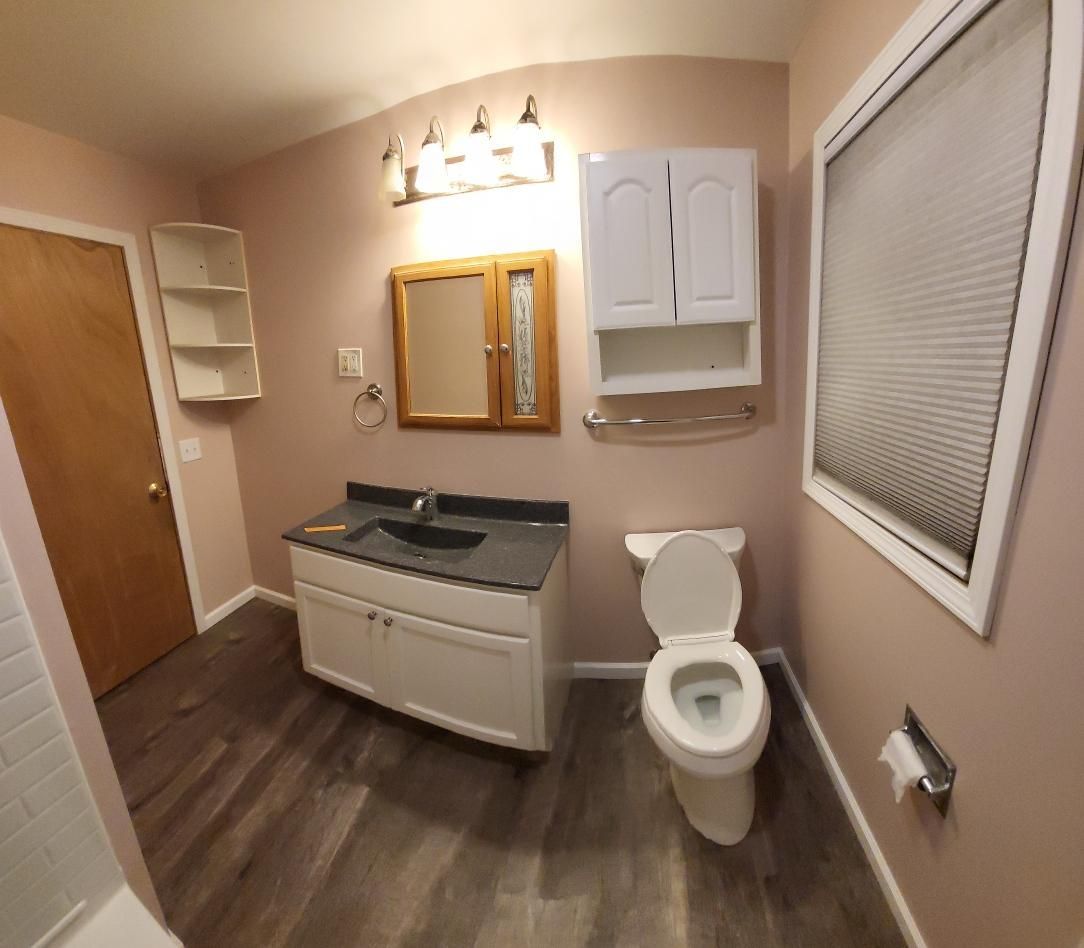 A bathroom with a toilet a sink and a mirror
