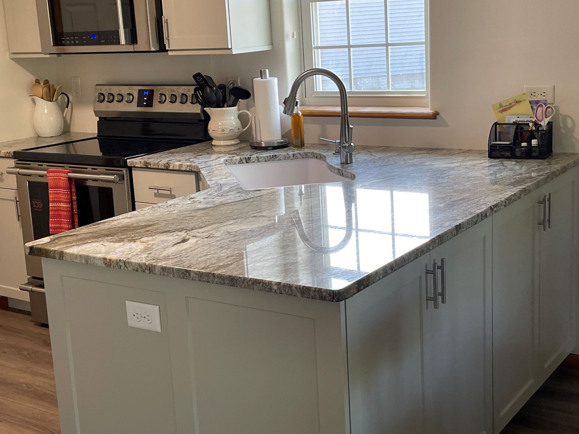 A kitchen with white cabinets , granite counter tops , a sink , and a stove.