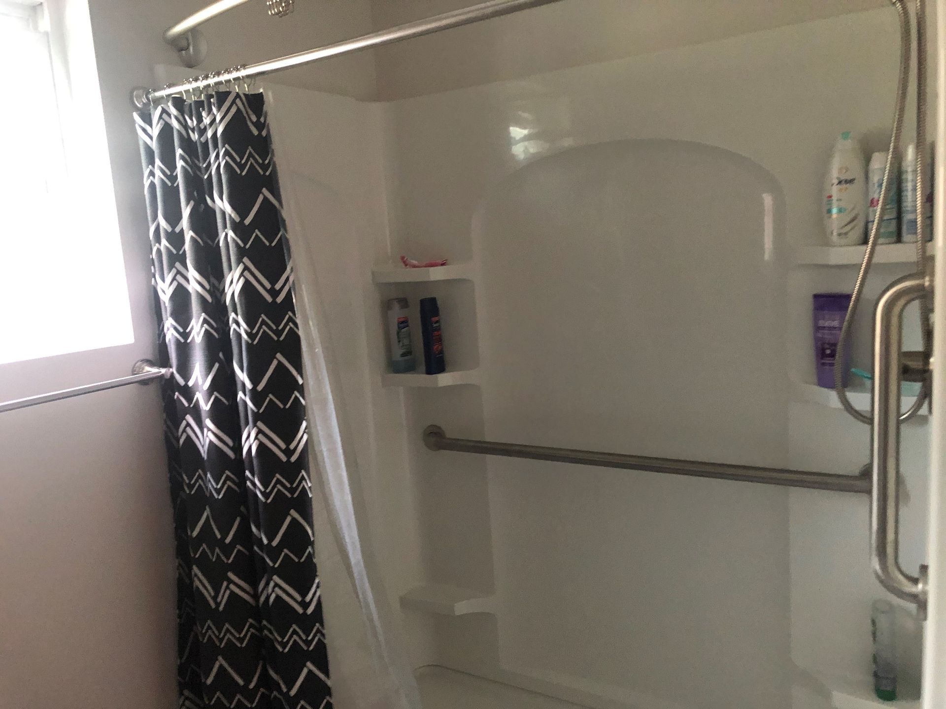 A bathroom with a shower stall and a black and white shower curtain.