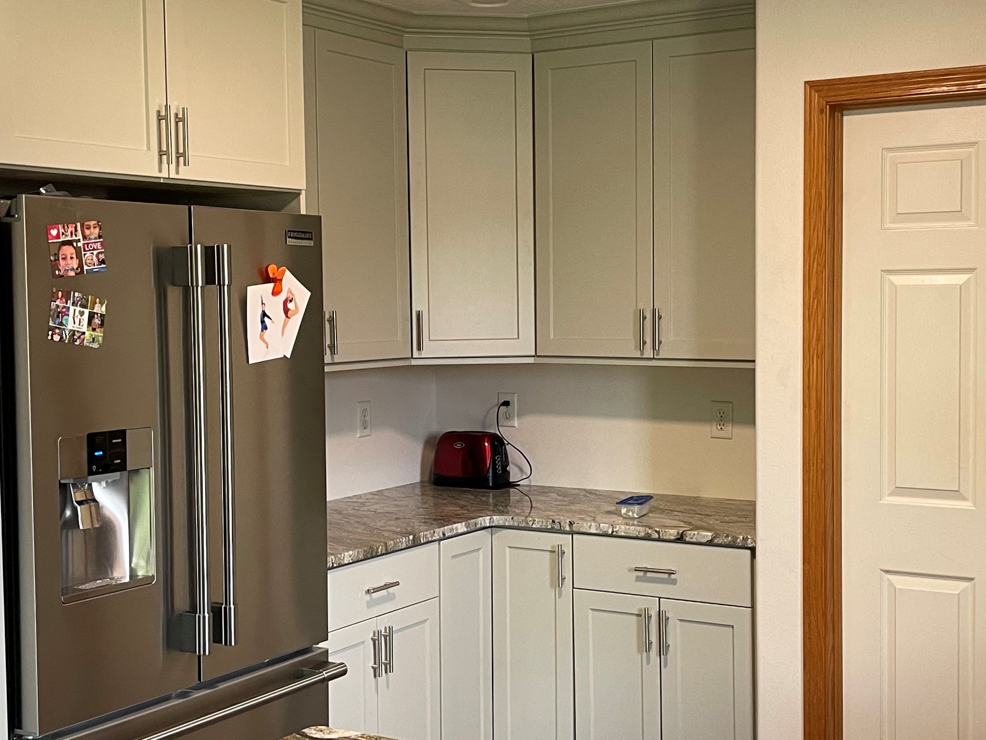 A kitchen with white cabinets and a stainless steel refrigerator.