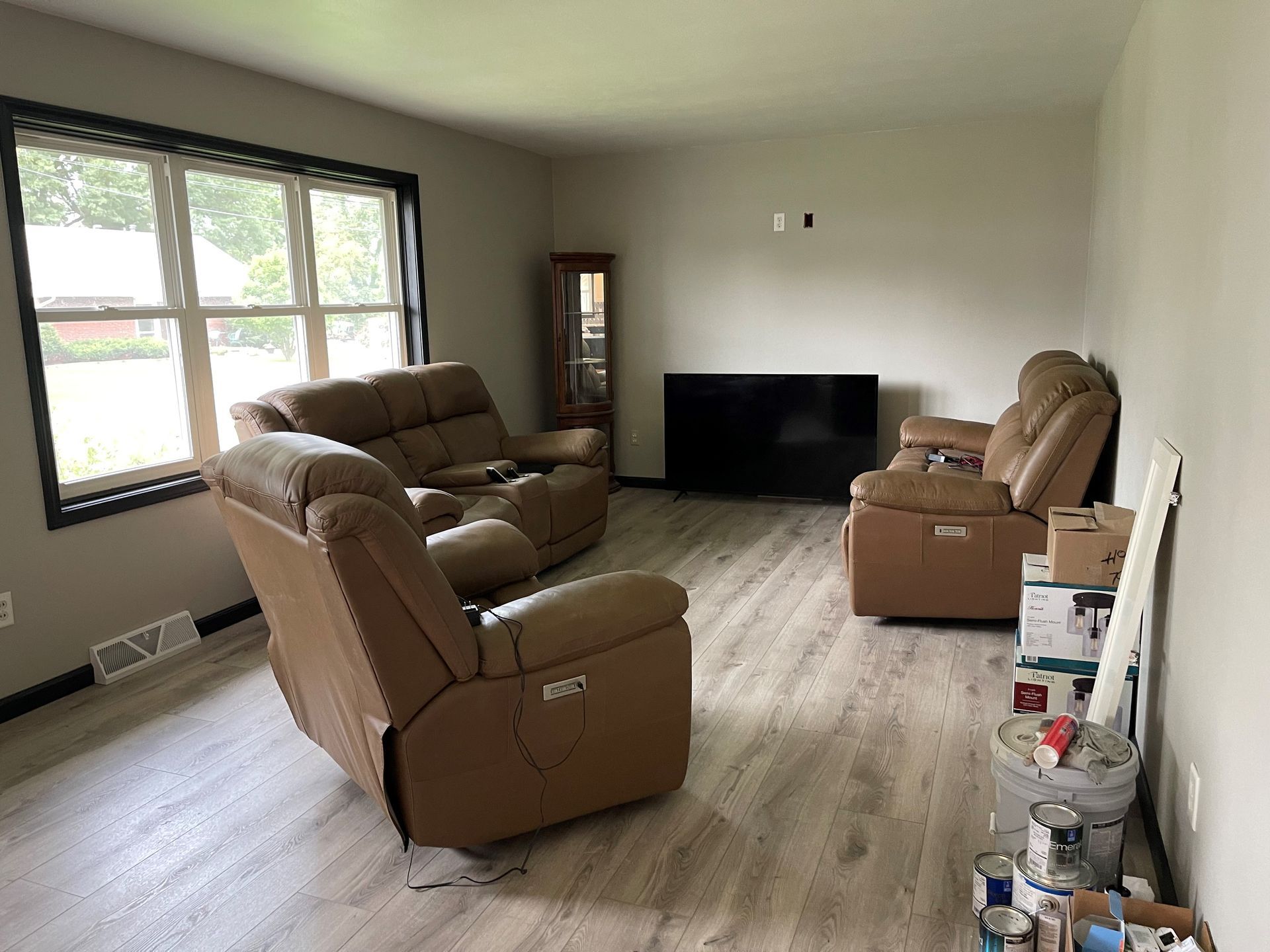 A living room with a couch , two chairs and a flat screen tv.