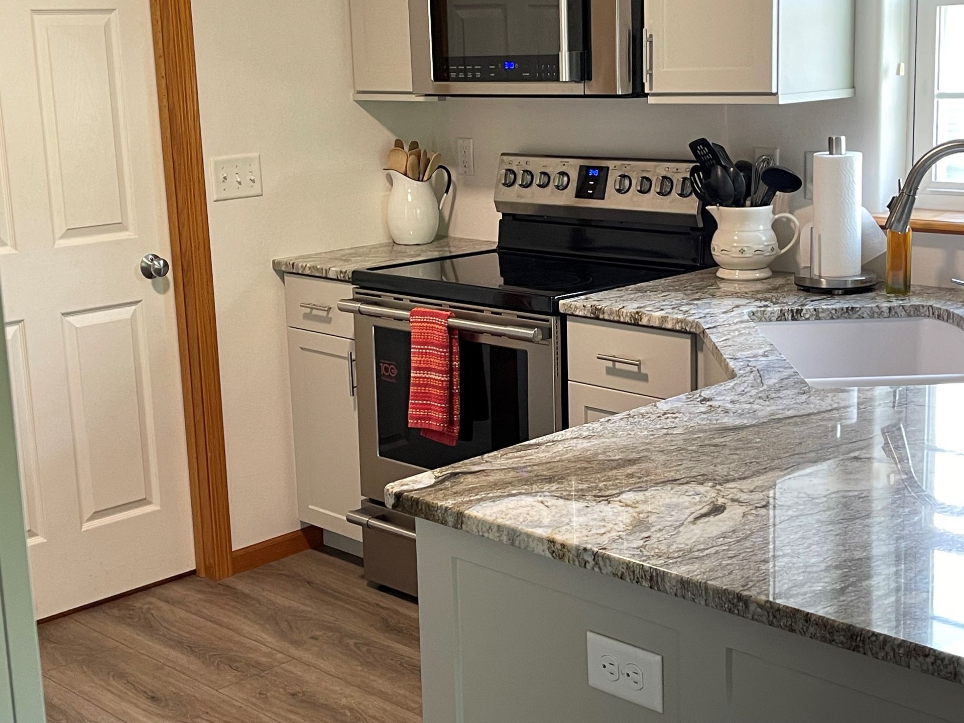 A kitchen with a stove , microwave , sink and cabinets.