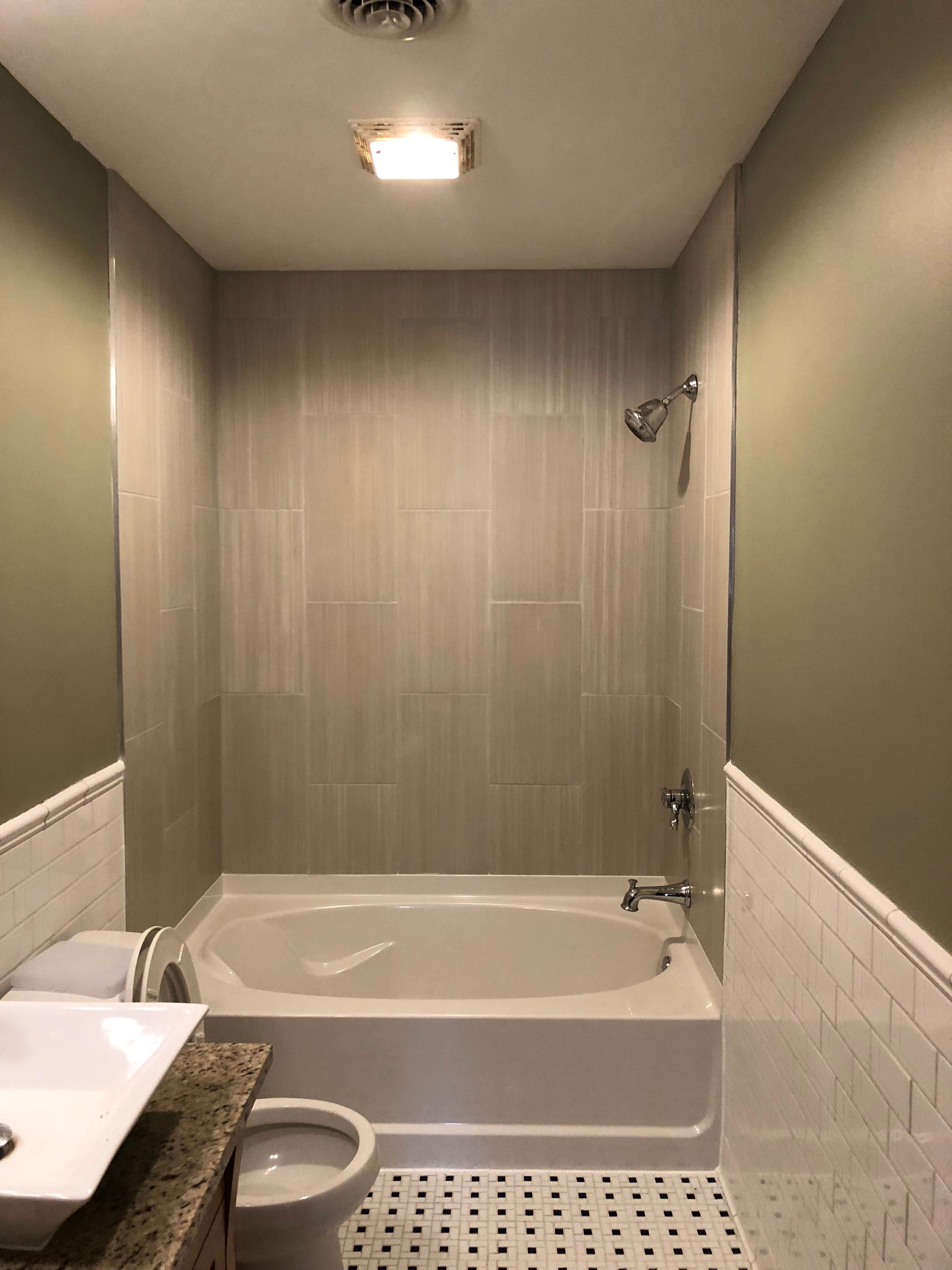 A bathroom with a tub , toilet , sink and mirror.