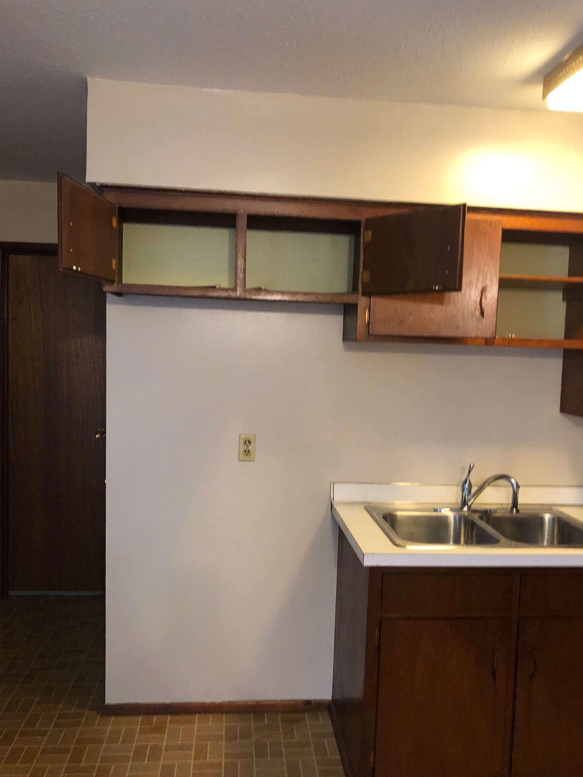 An empty kitchen with two sinks and cabinets