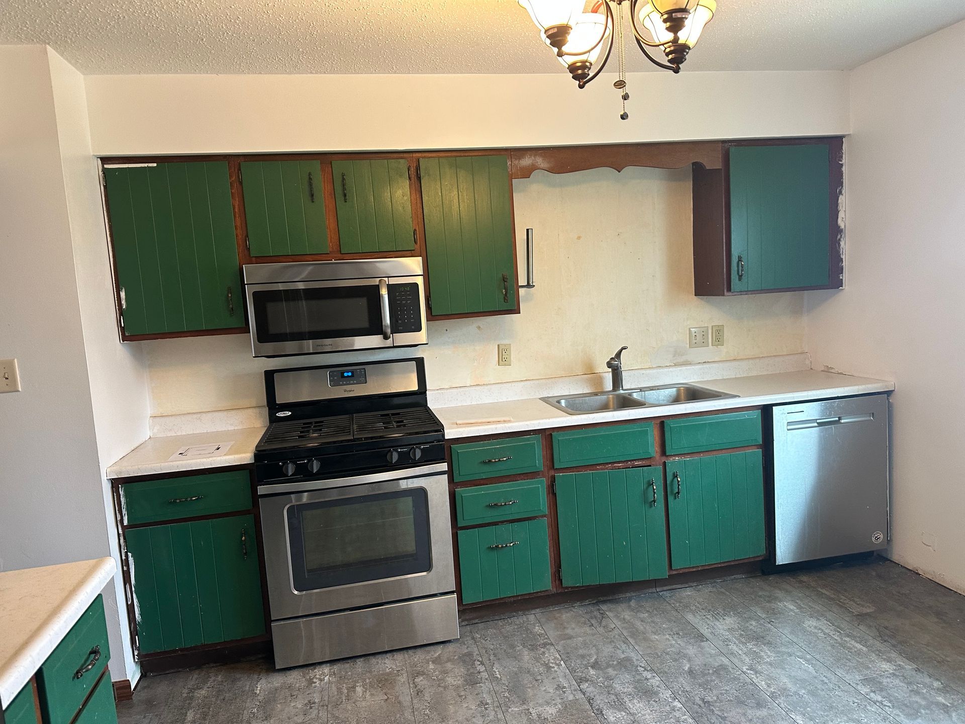 A kitchen with green cabinets and stainless steel appliances