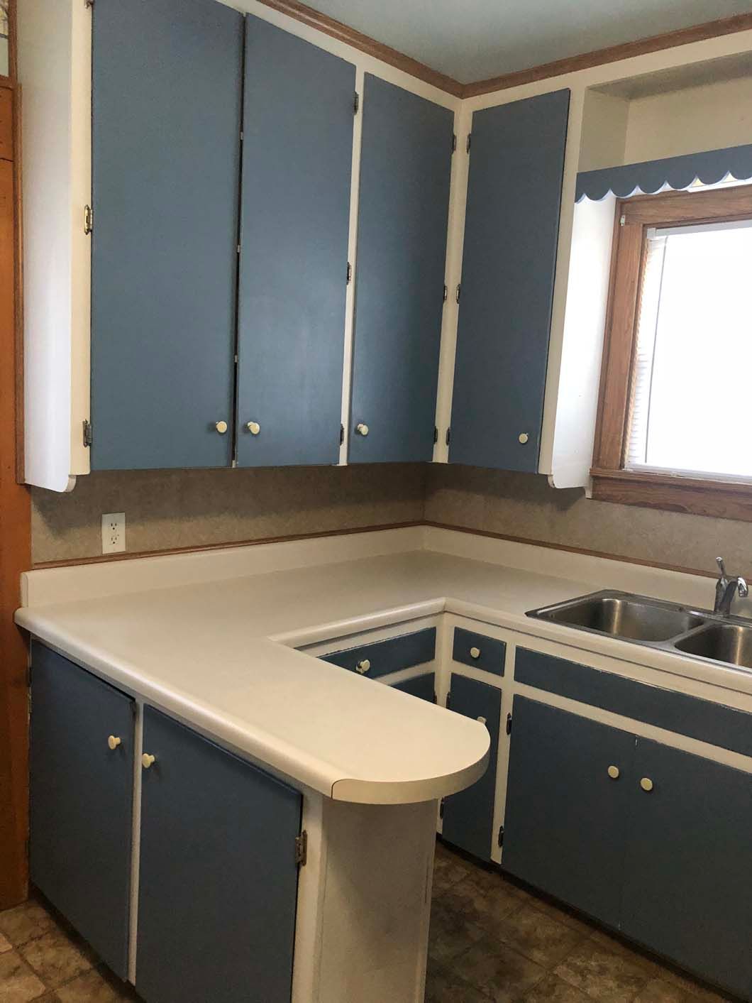 A kitchen with blue cabinets and white counter tops