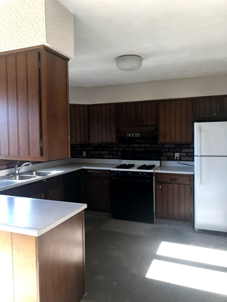 A kitchen with brown cabinets and a white refrigerator