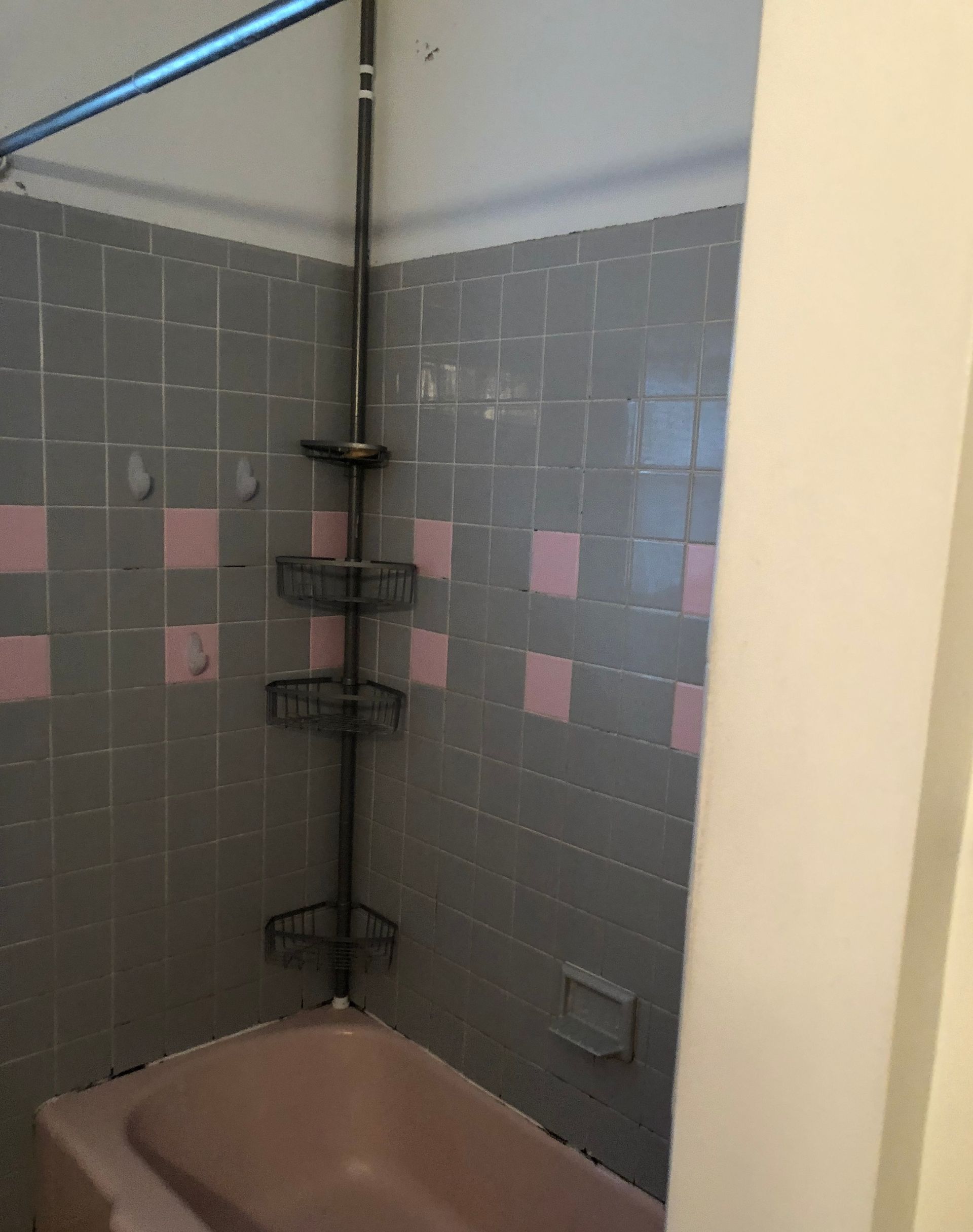 A bathroom with pink and gray tiles and a bathtub.