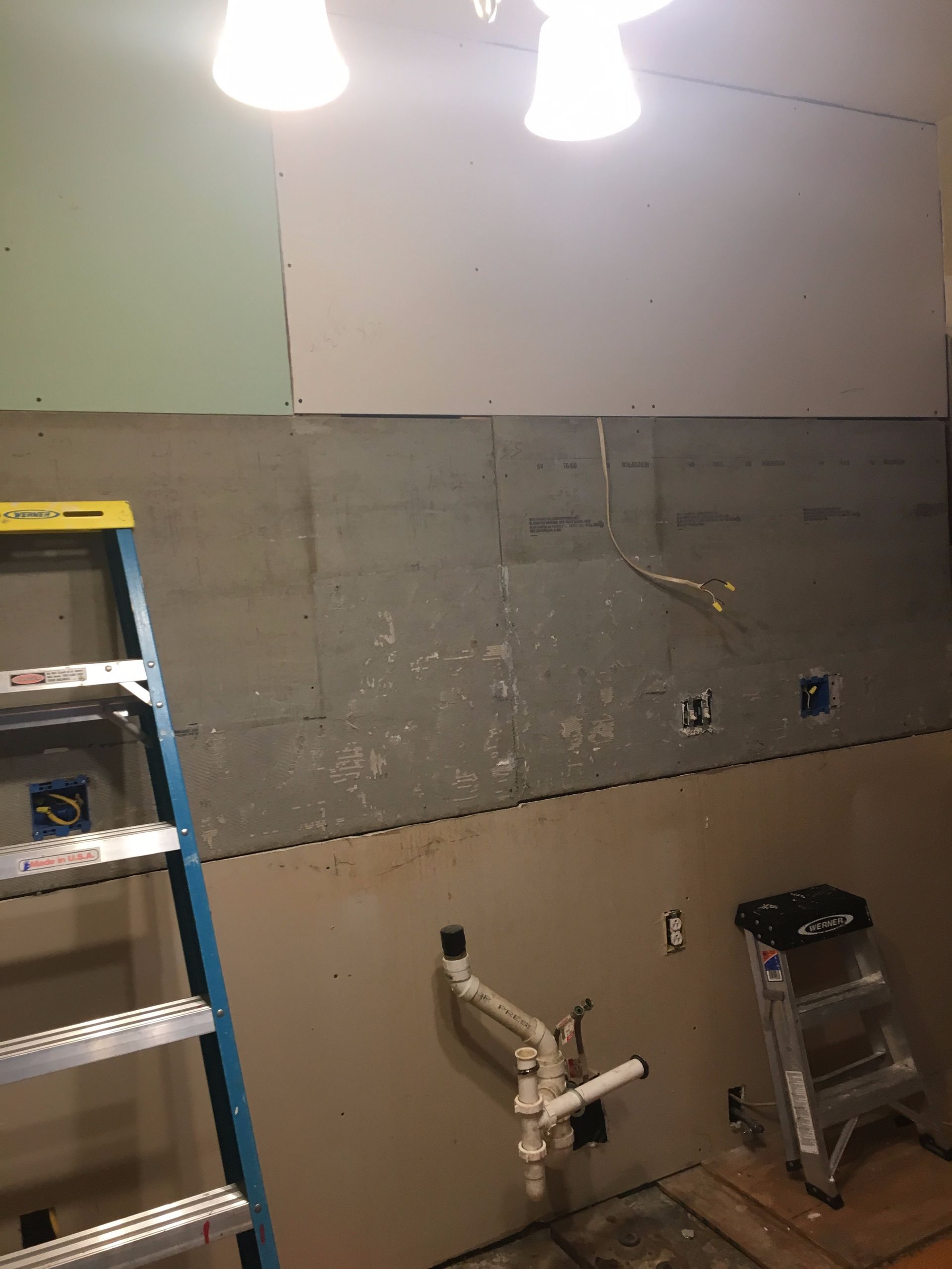 A bathroom under construction with a ladder and a stool.