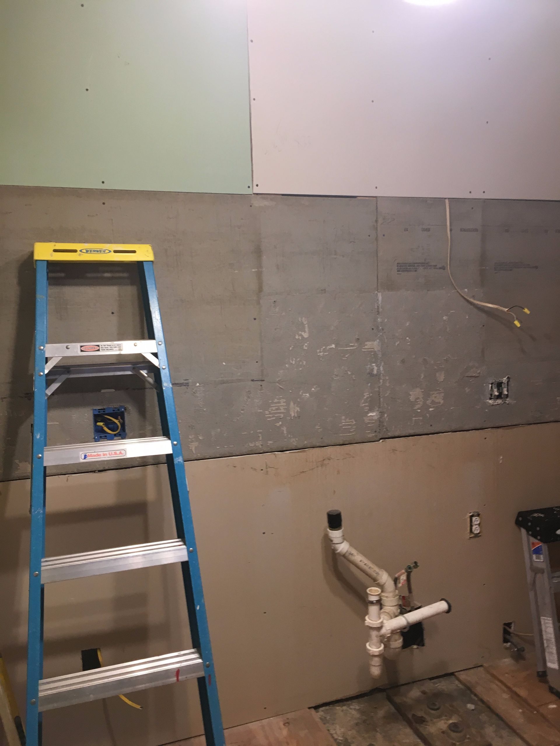 A blue ladder is leaning against a wall in a bathroom.