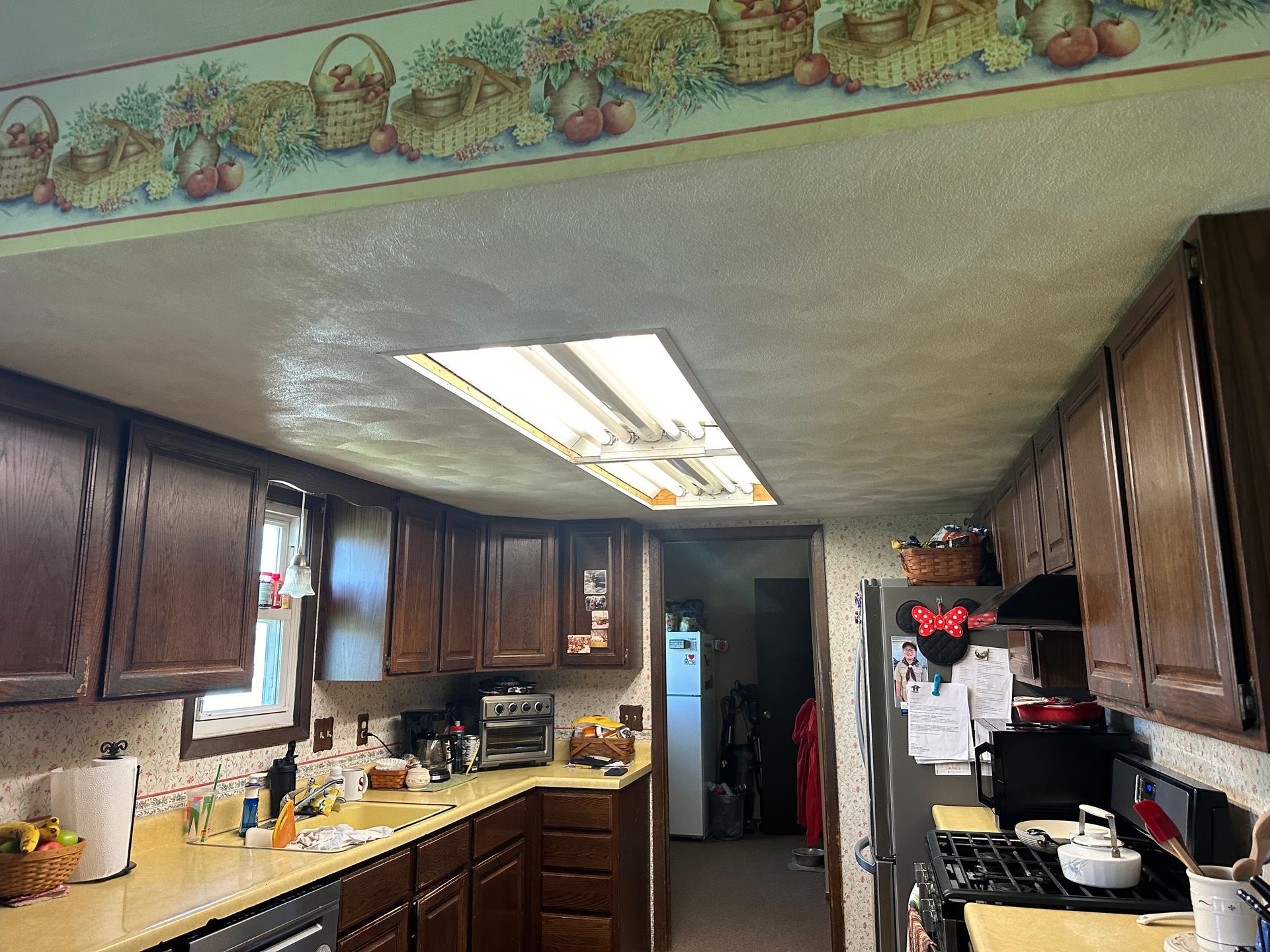 A kitchen with wooden cabinets and a floral wallpaper