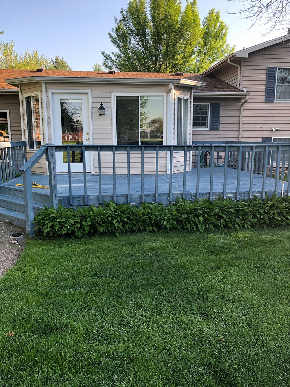 A small house with a blue deck and stairs in front of it.
