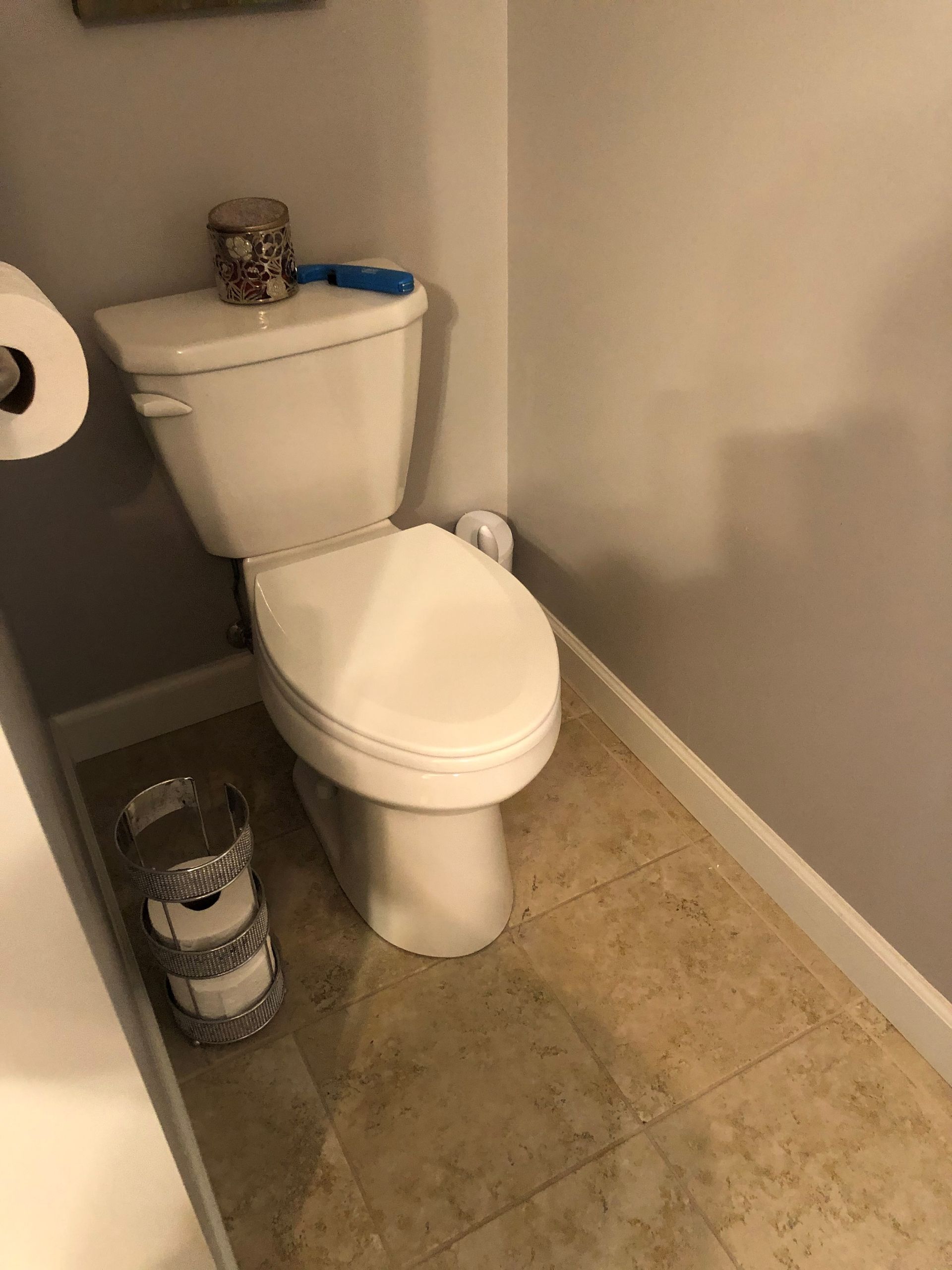 A toilet is sitting in a bathroom next to a stack of toilet paper rolls.