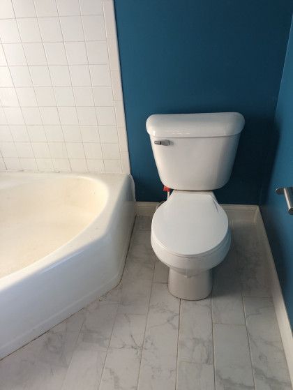 A bathroom with a toilet , bathtub and blue walls.