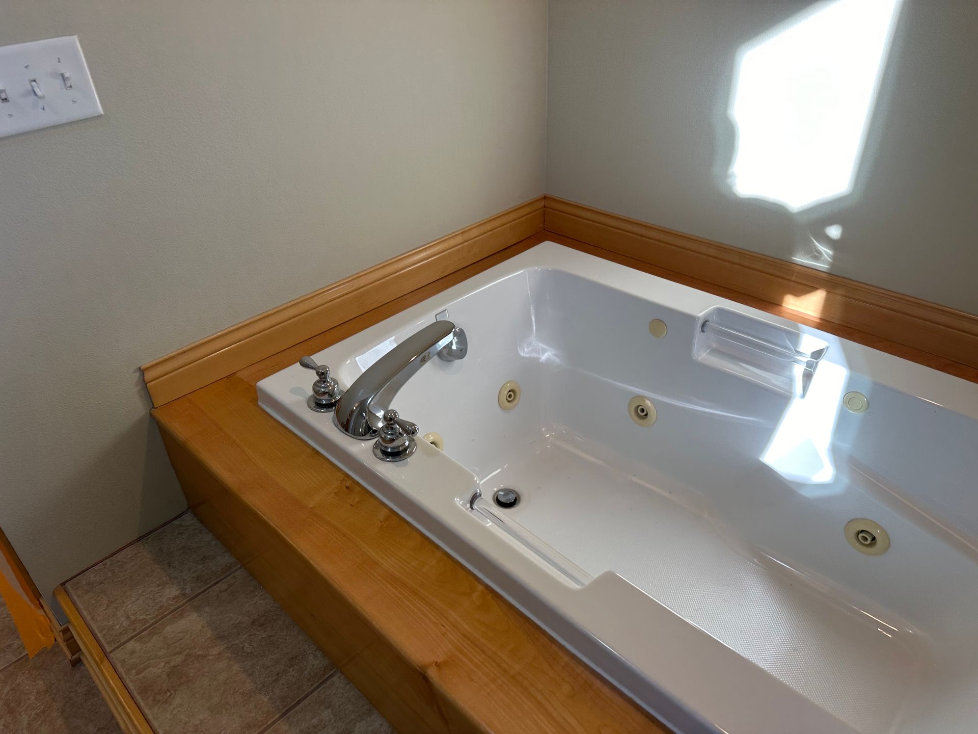 A jacuzzi tub in a bathroom with a wooden counter top