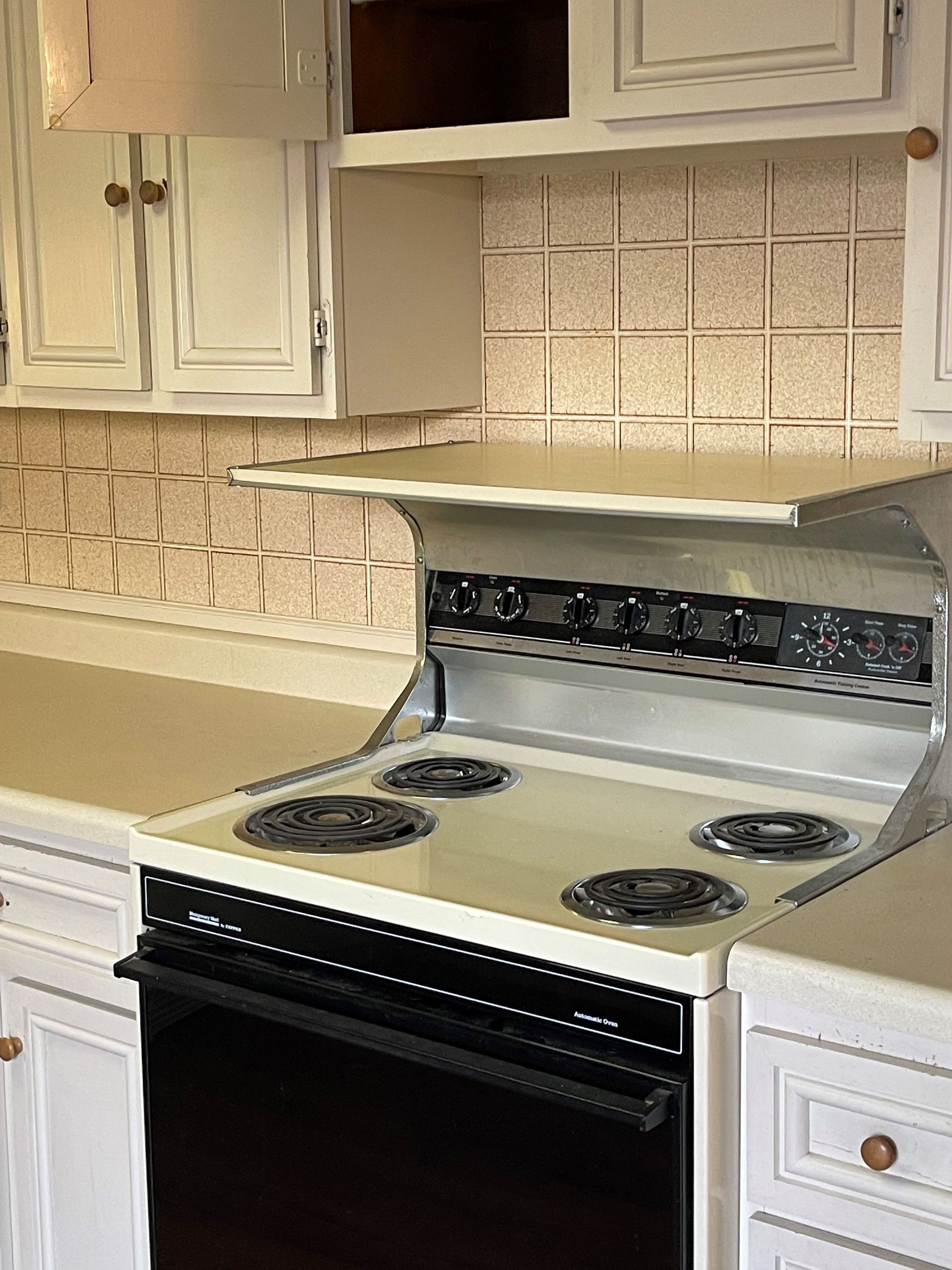A kitchen with a stove top oven and white cabinets