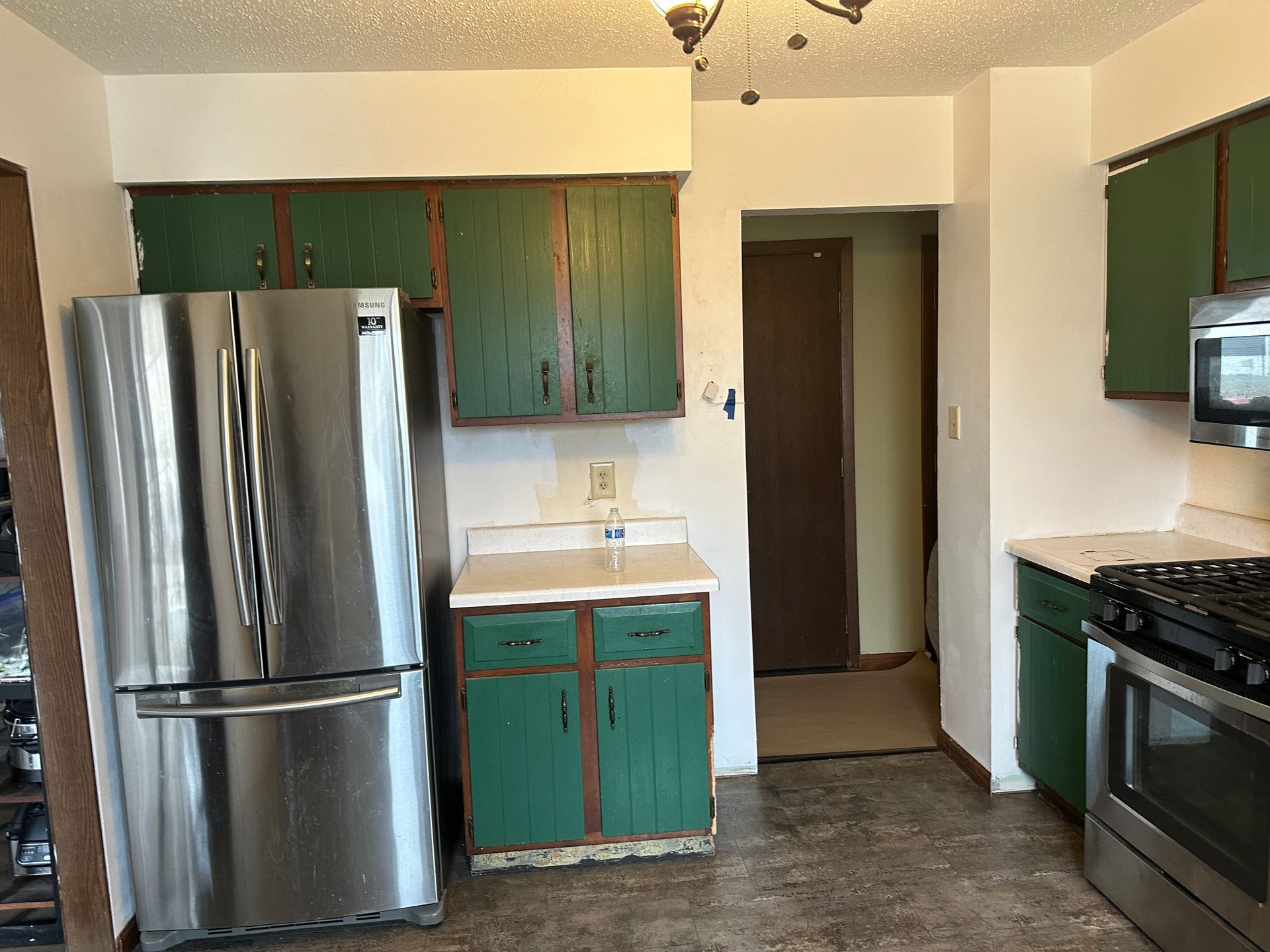 A kitchen with green cabinets and a stainless steel refrigerator