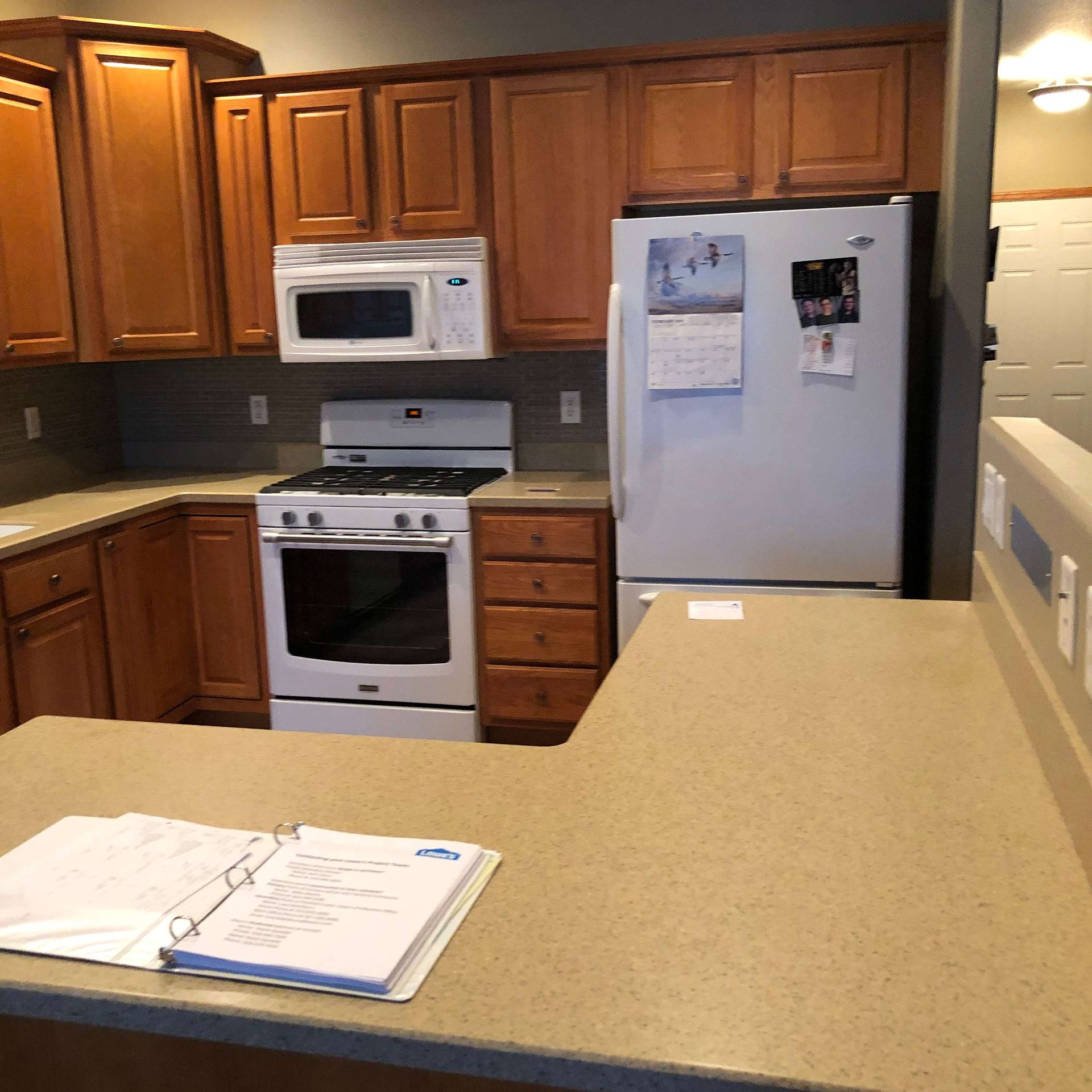 A kitchen with a stove a refrigerator and a microwave