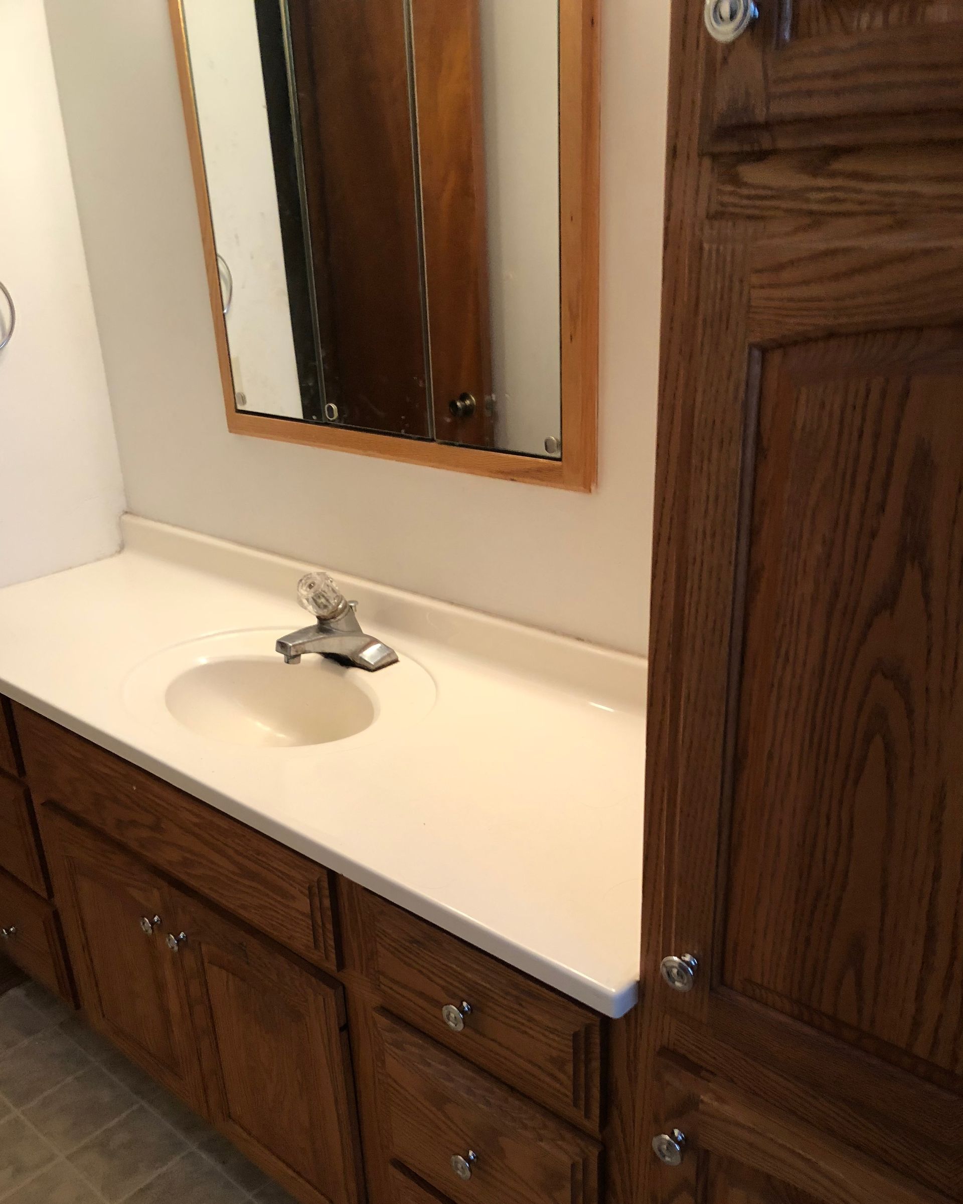A bathroom with a sink , mirror and wooden cabinets